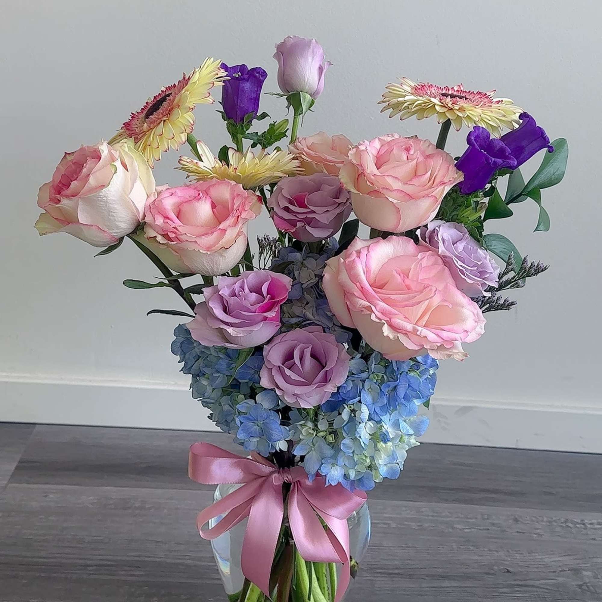 Pink and lavender roses with blue hydrangeas in a glass vase, photo 2 of 2