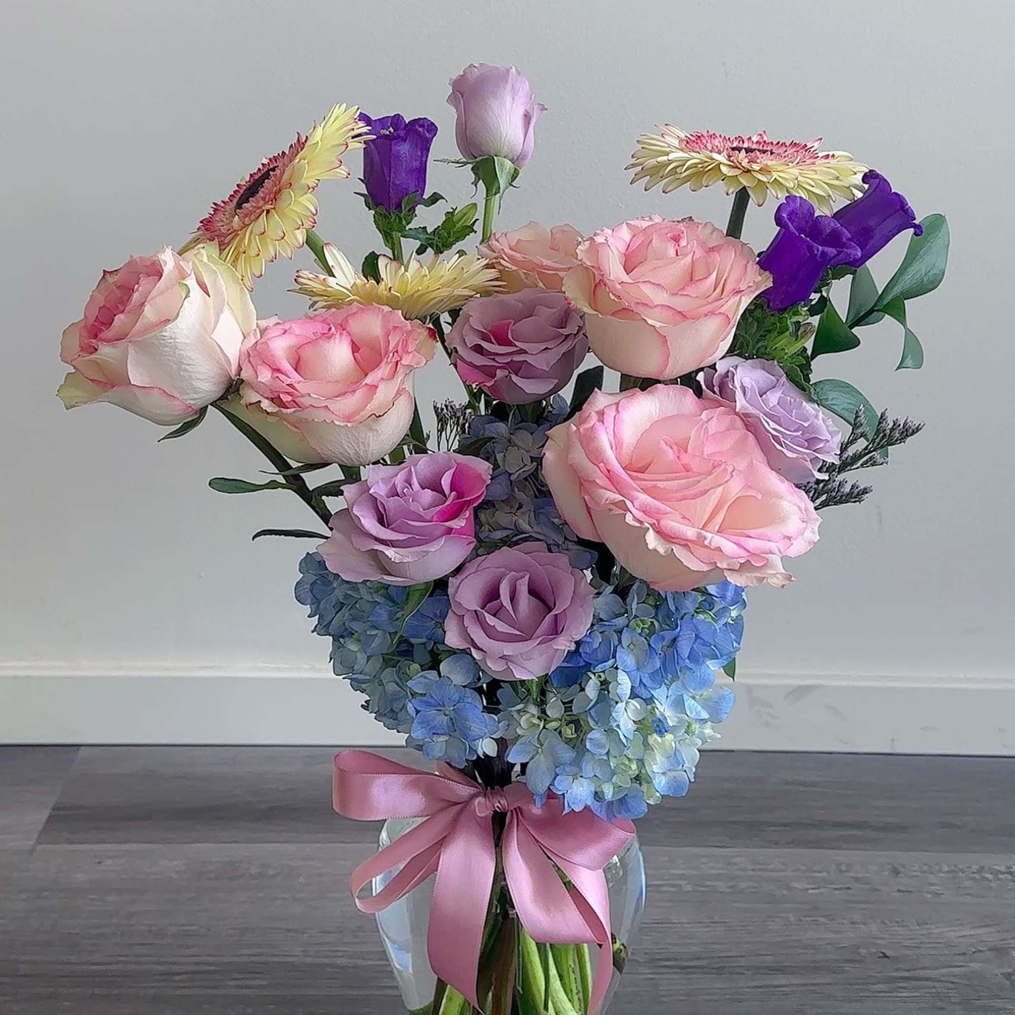 Pink and lavender roses with blue hydrangeas in a glass vase