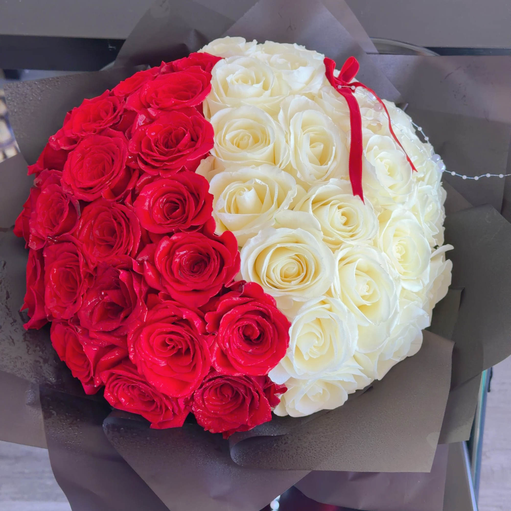 Red and white rose bouquet wrapped in dark paper