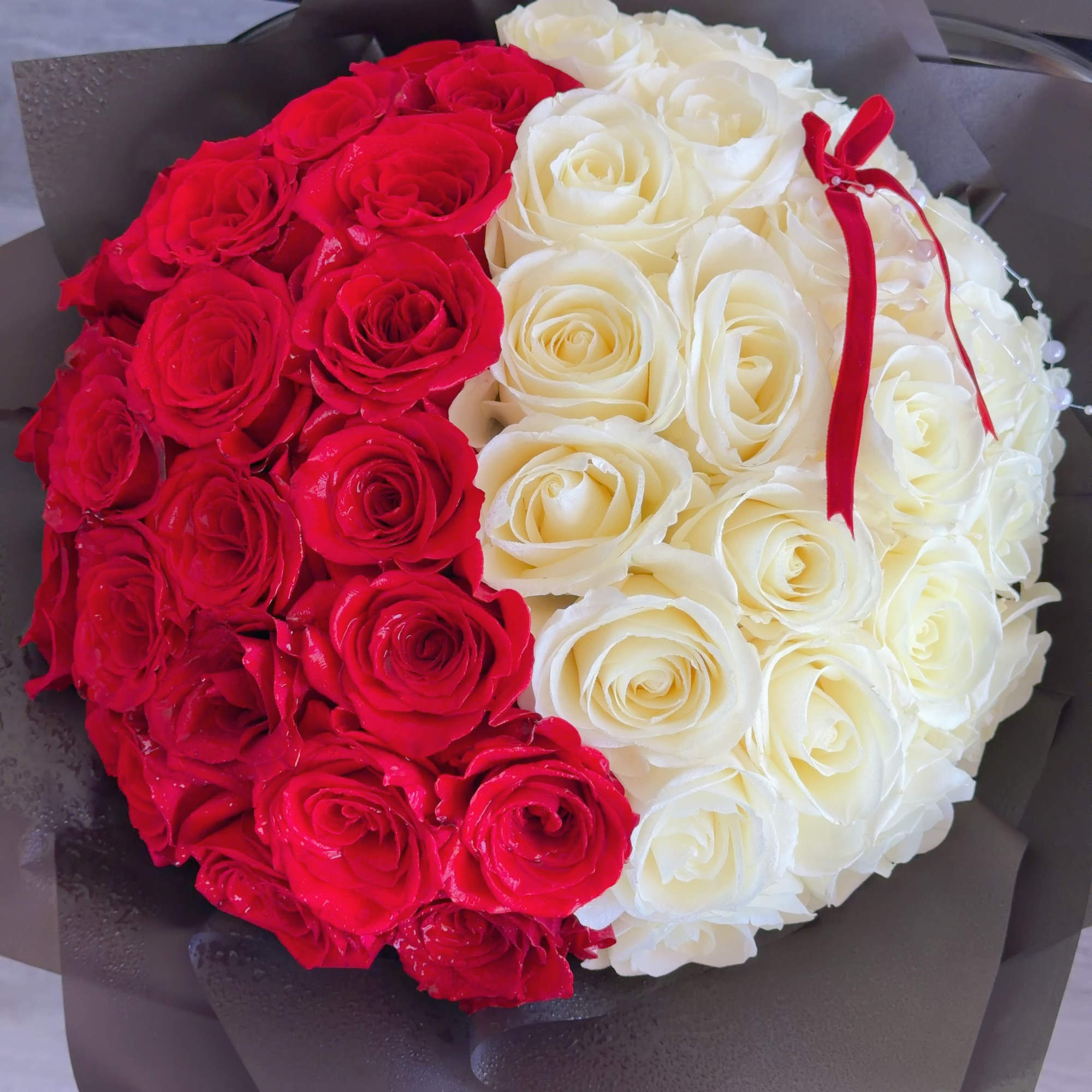 Round bouquet of red and white roses wrapped in dark paper, photo 2 of 4