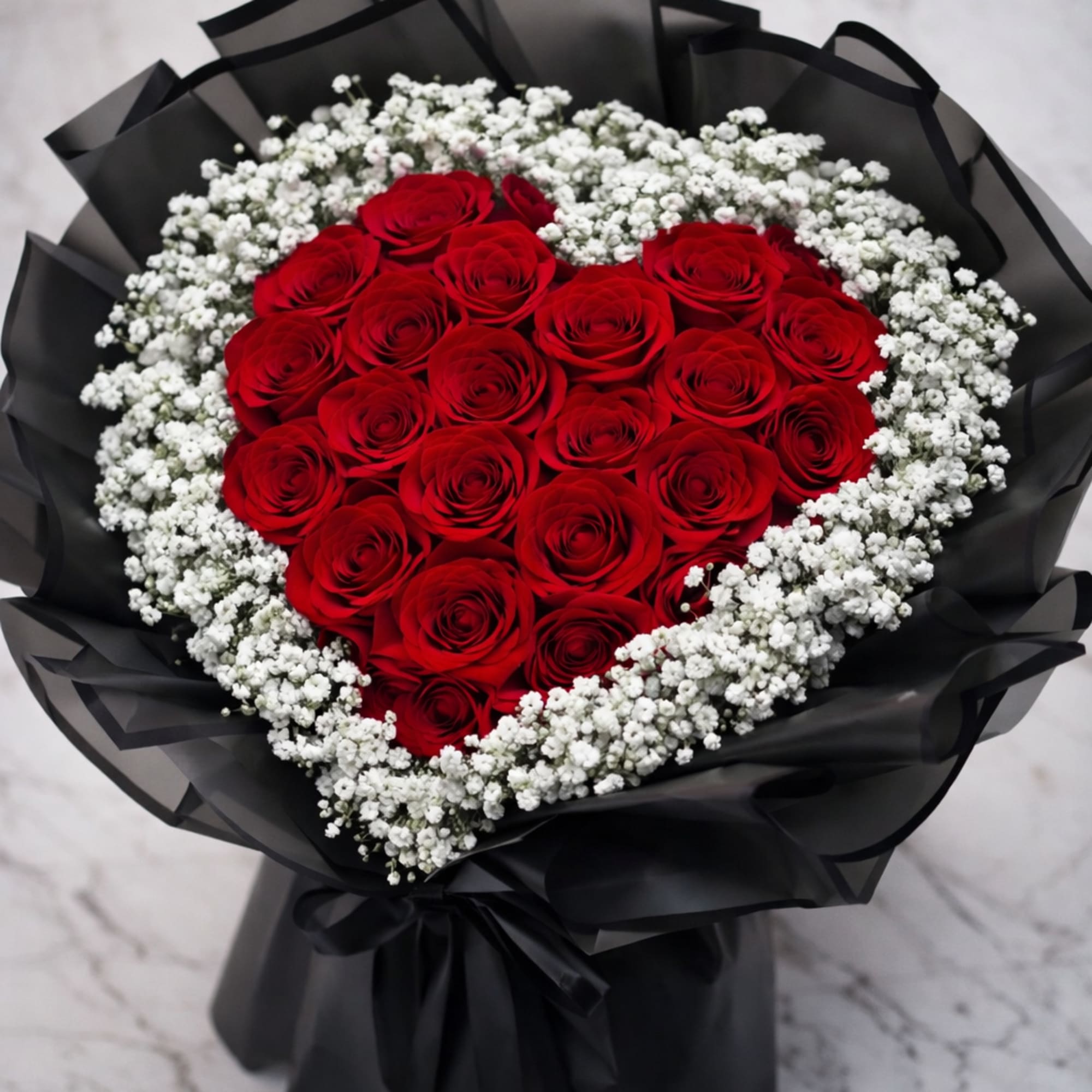Heart-shaped bouquet of red roses with white baby's breath in black wrap