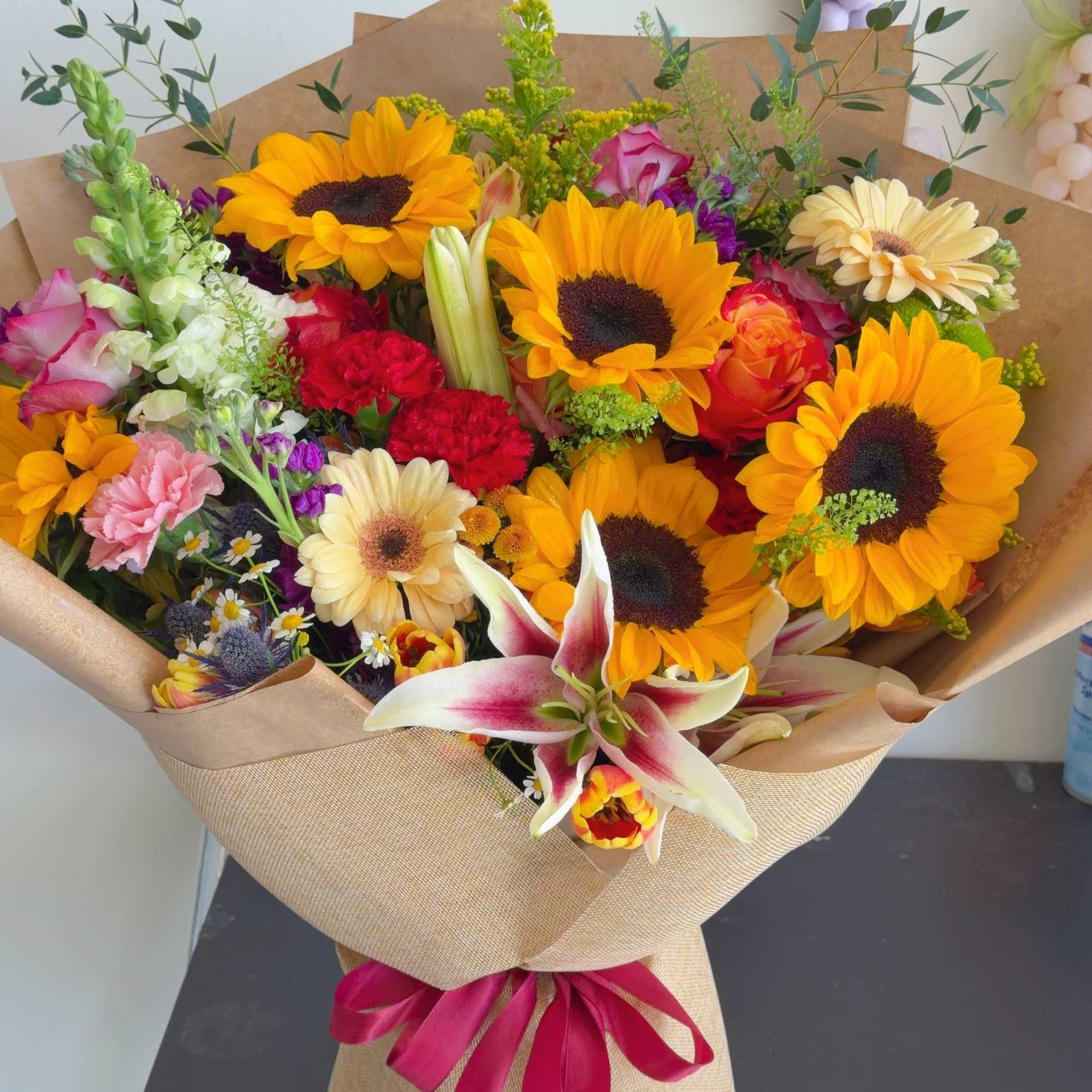 Radiant Summer Bloom is a vibrant bouquet featuring cheerful sunflowers, elegant lilies