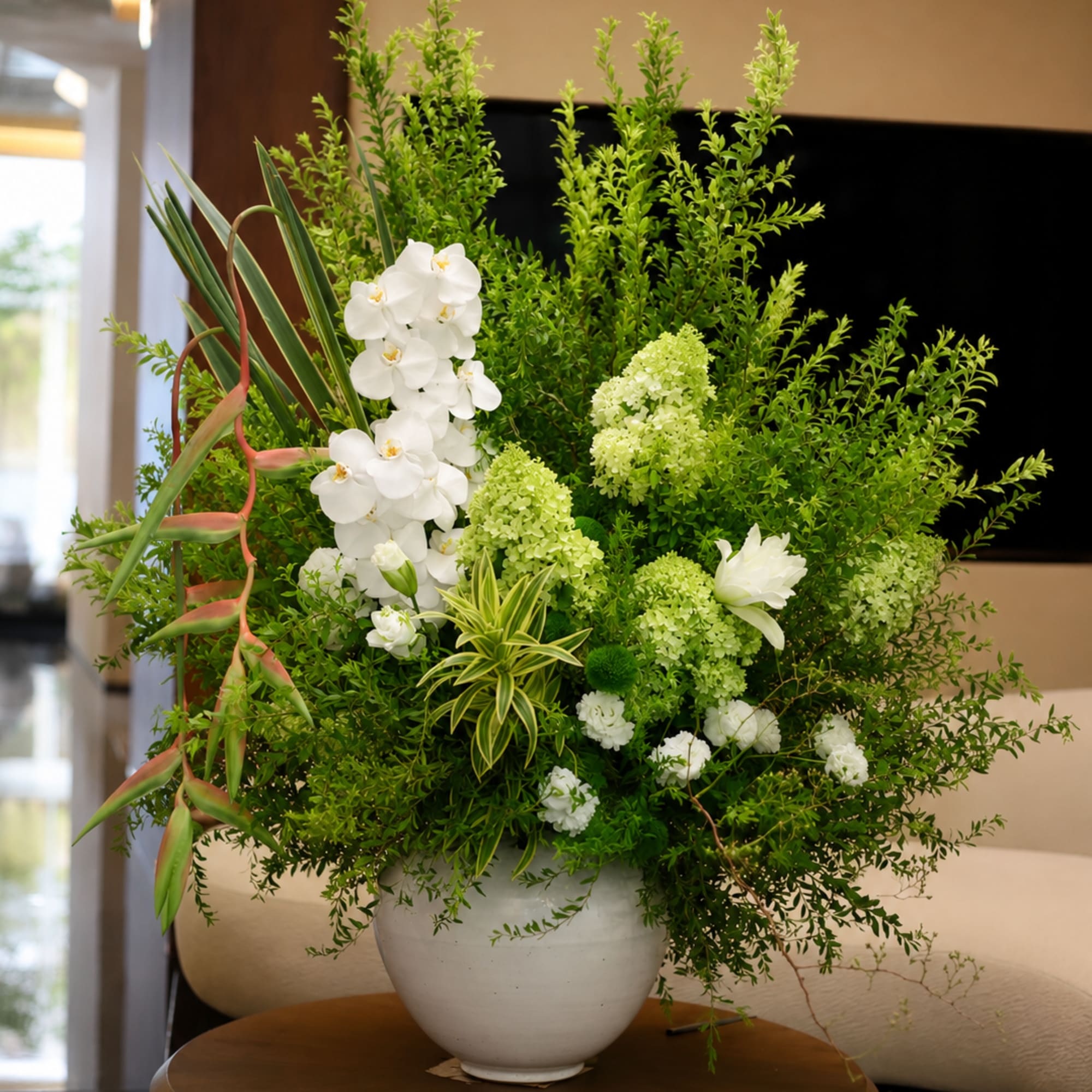 Large green and white floral arrangement in a white vase