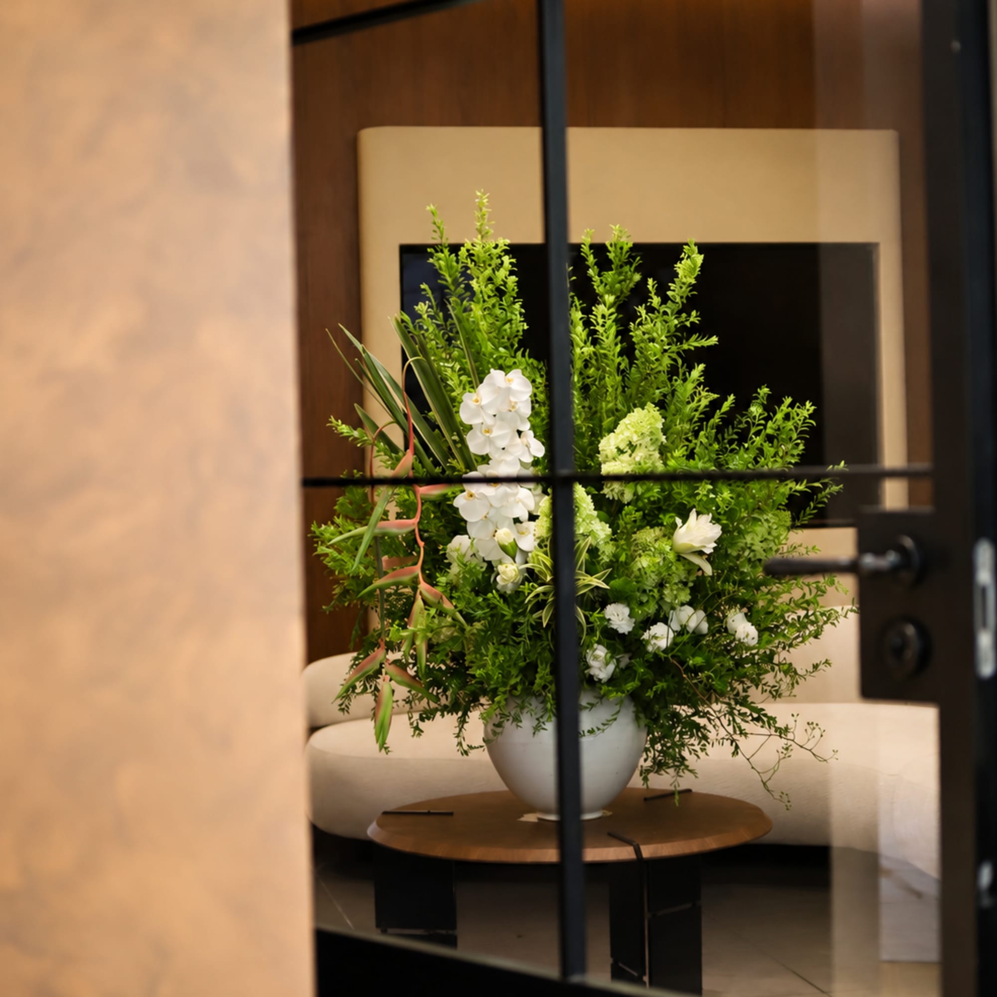 White orchid arrangement in a white vase on a table