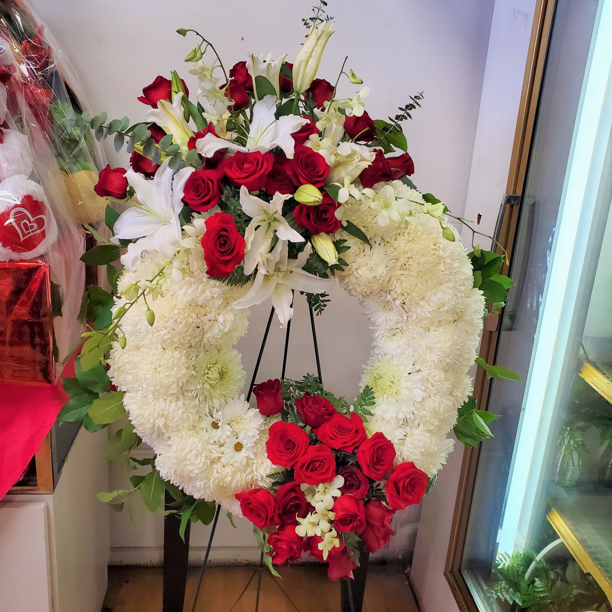Large red and white floral funeral wreath on a stand