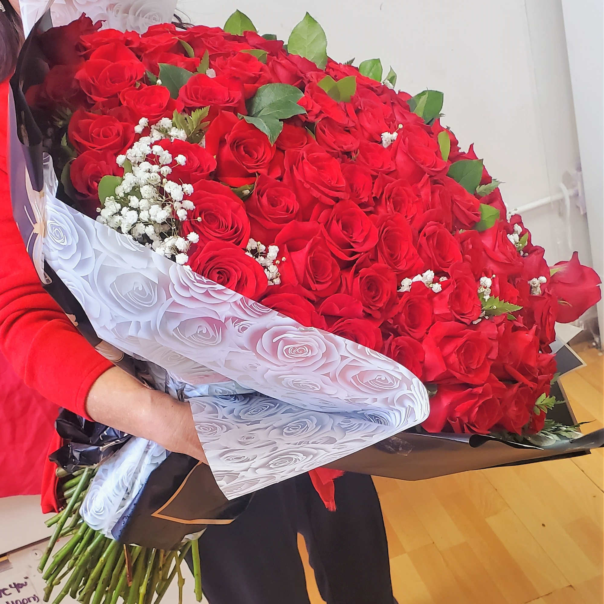 Large bouquet of red roses with white baby's breath in decorative wrap
