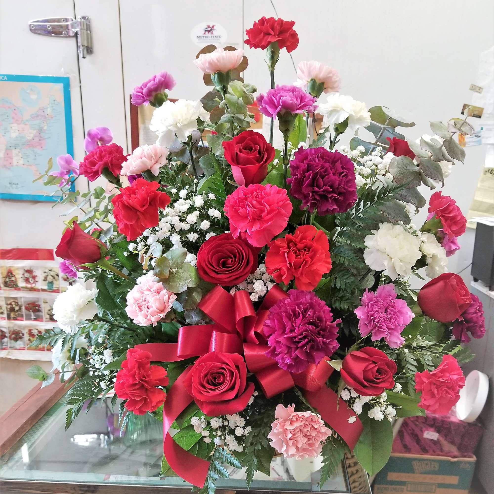 Large bouquet of red, pink, and white flowers with a red ribbon bow