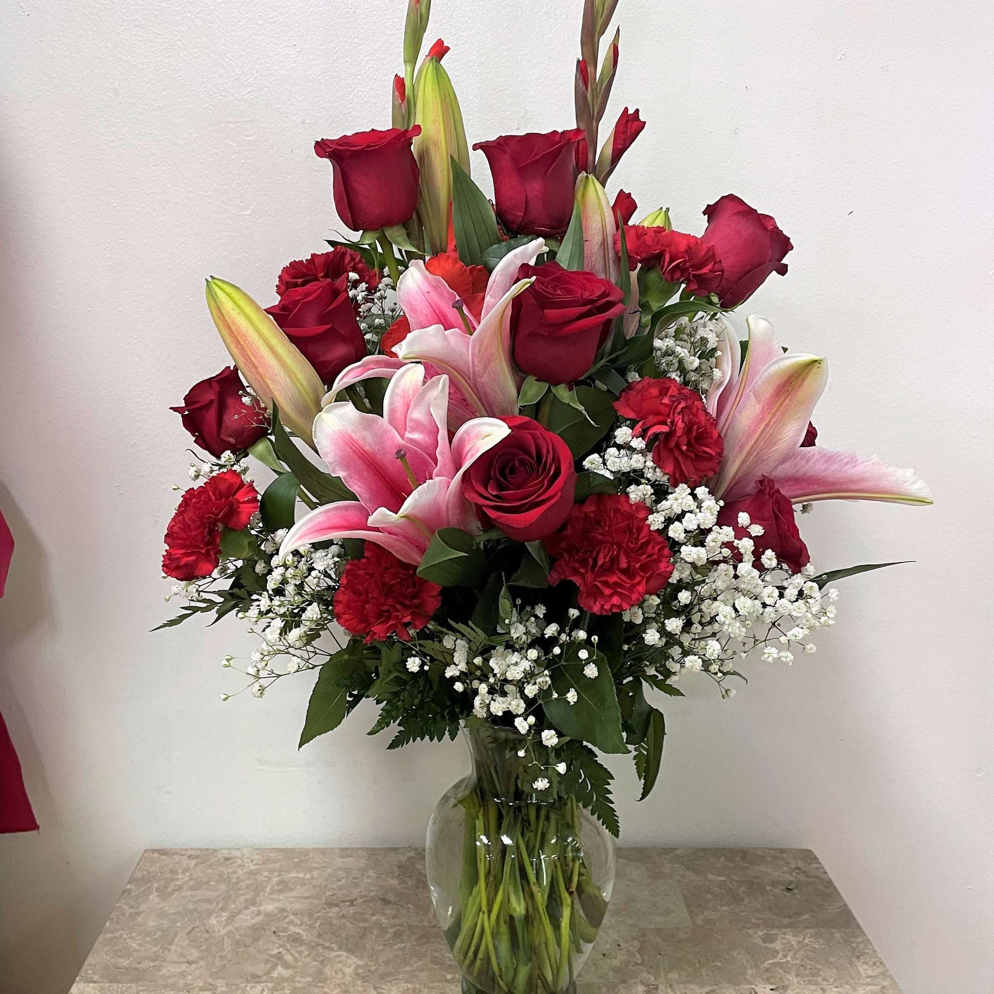 Red roses and pink lilies in a clear glass vase