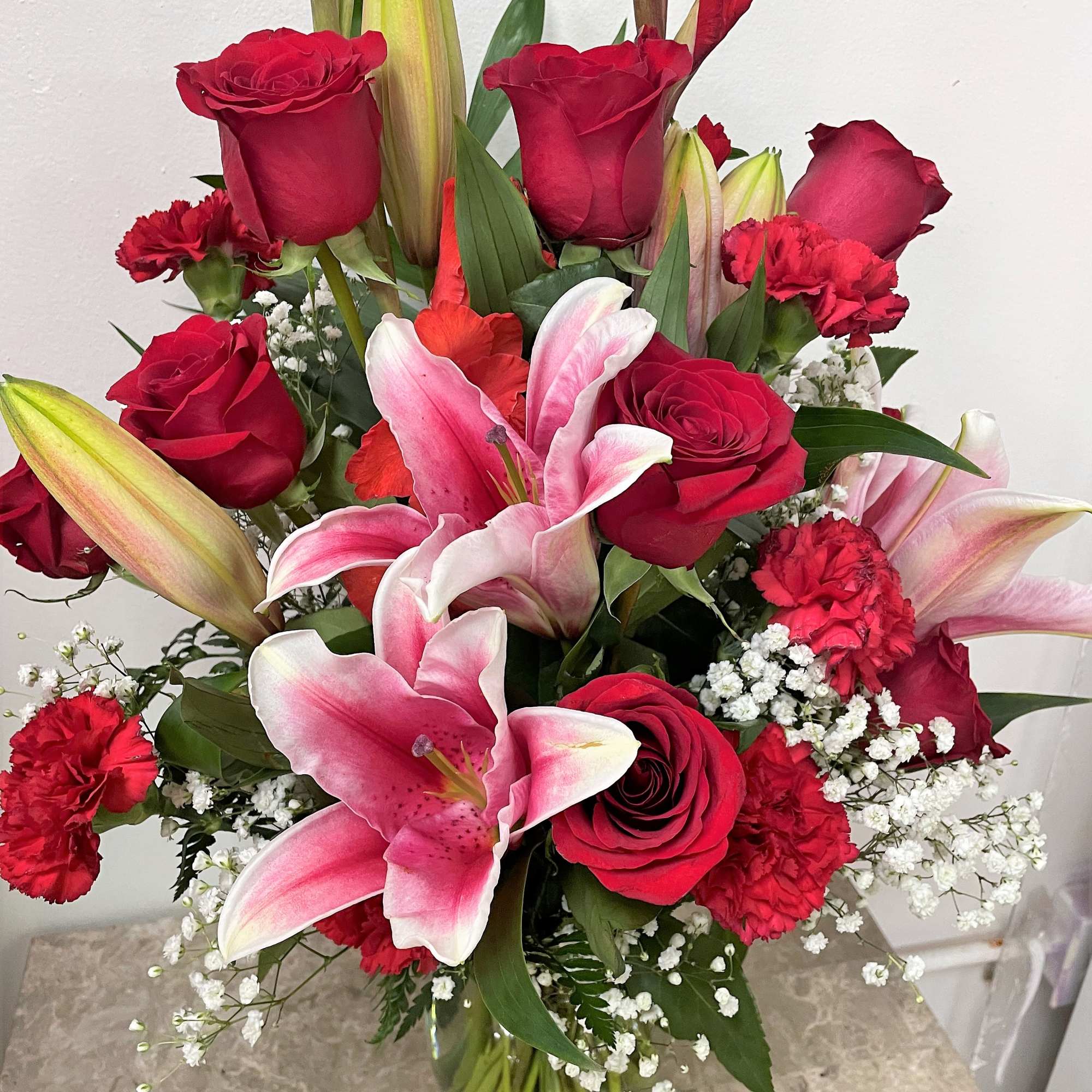 Bouquet of red roses and pink lilies in a clear glass vase