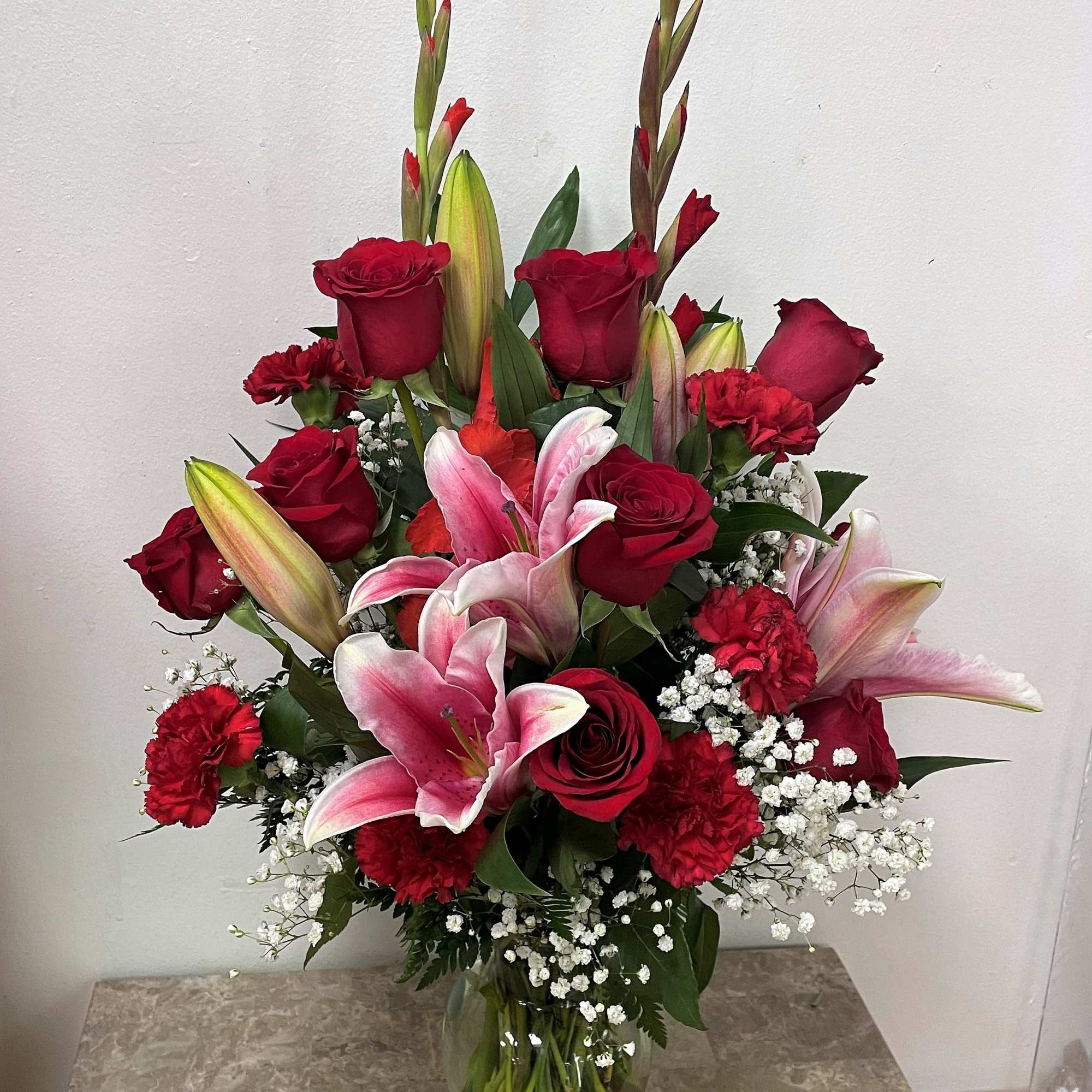 Red roses and pink lilies arranged in a glass vase