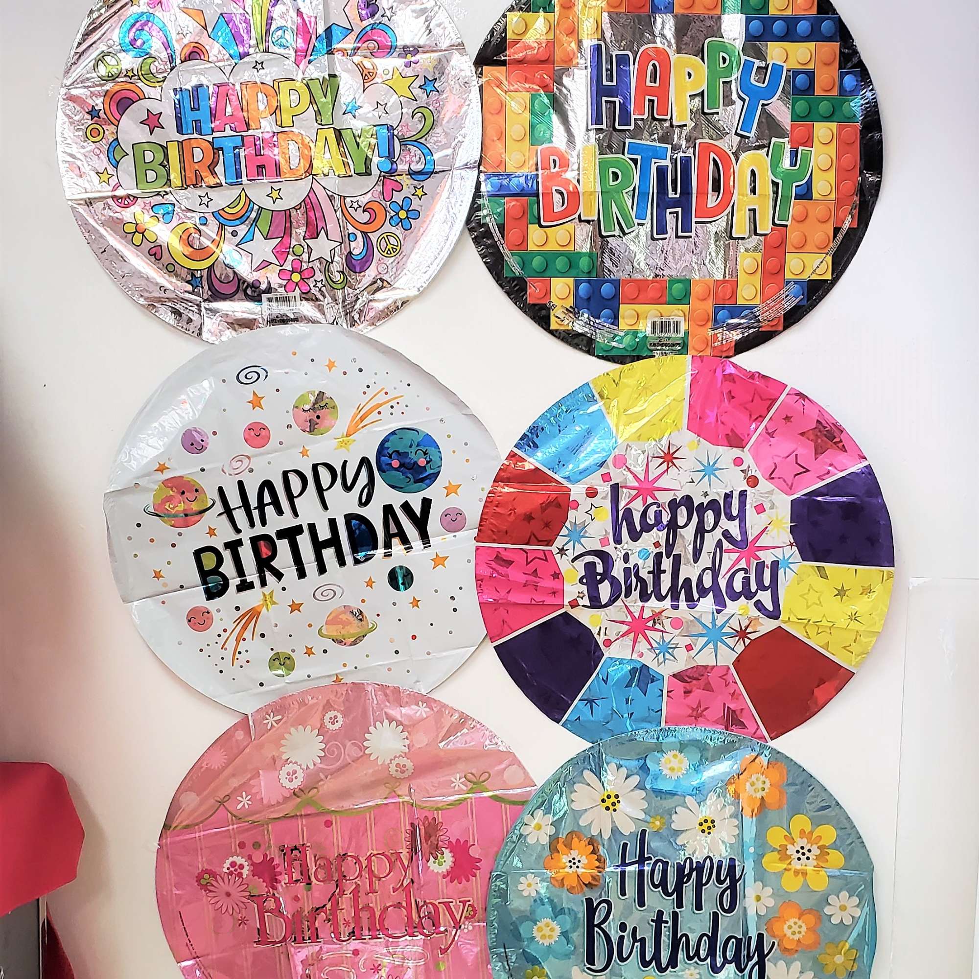 Six round birthday balloons with colorful printed designs on a wall
