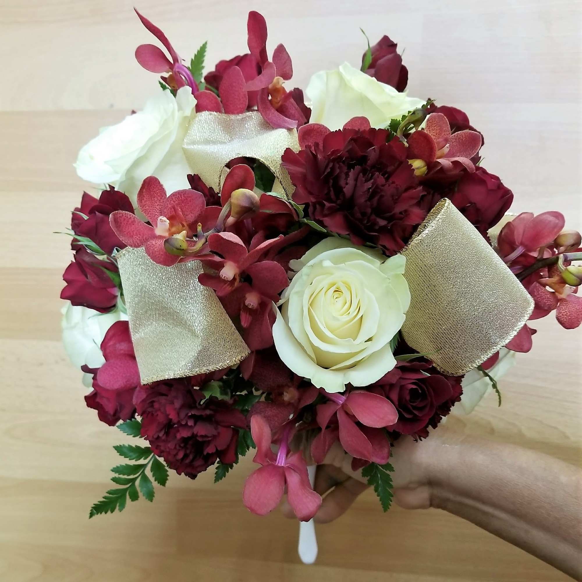 Bouquet of white roses, burgundy flowers, and pink orchids with gold ribbon