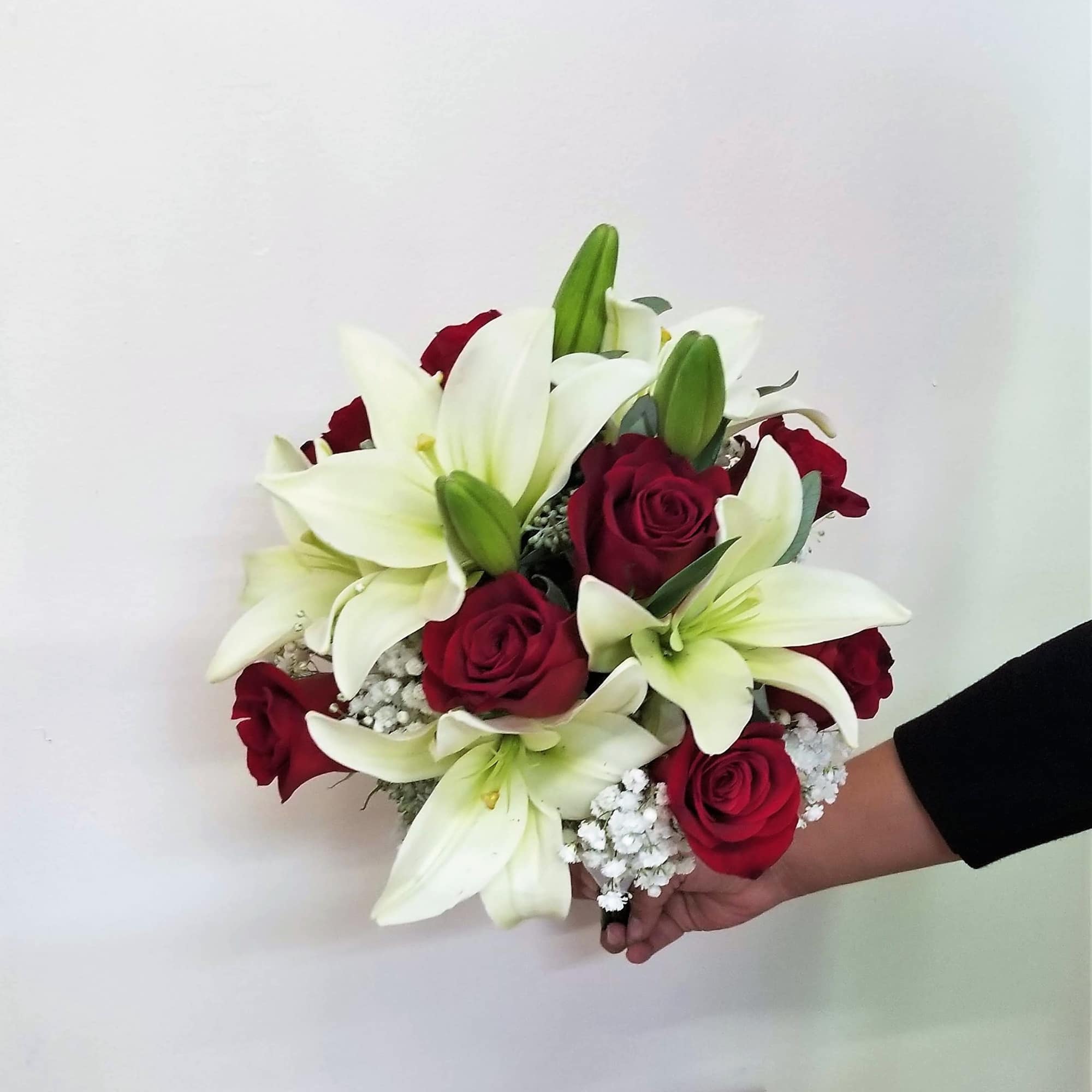 Bouquet of white lilies and red roses held in hand