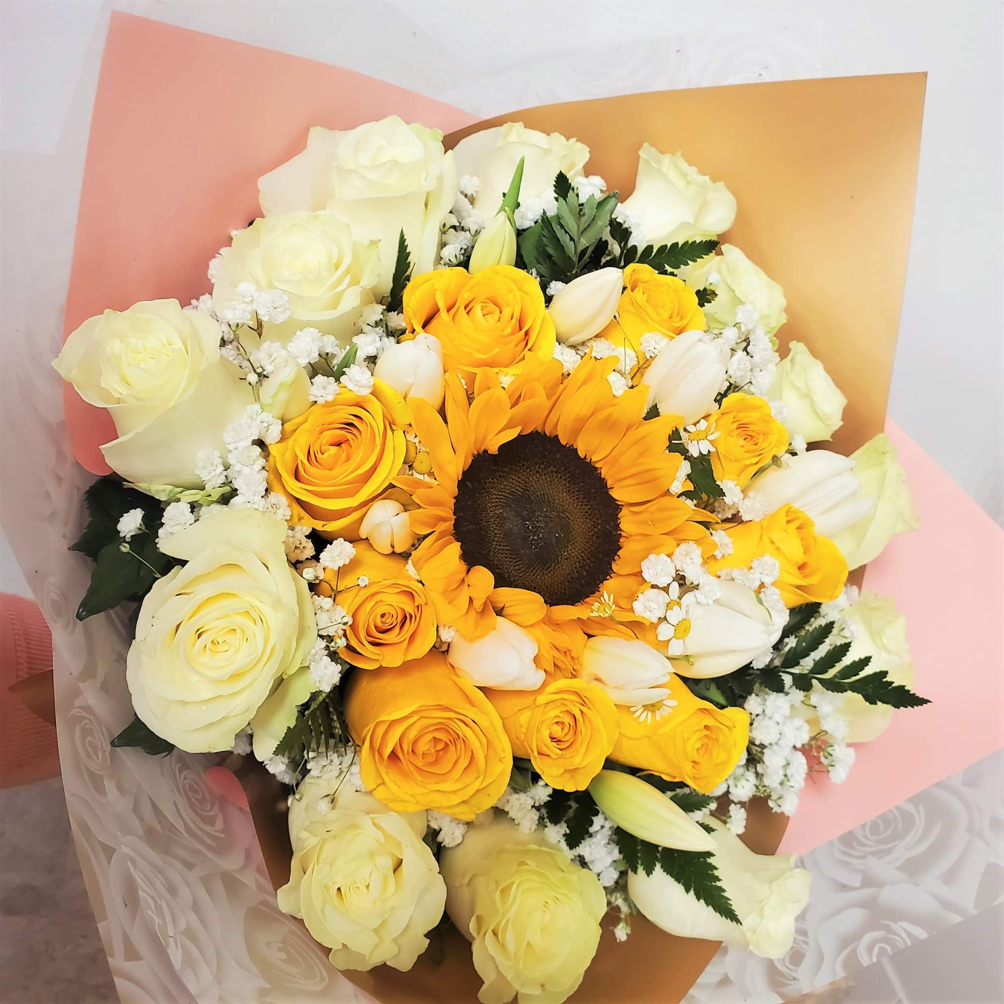 Bouquet of yellow and white roses with a sunflower in pastel wrapping
