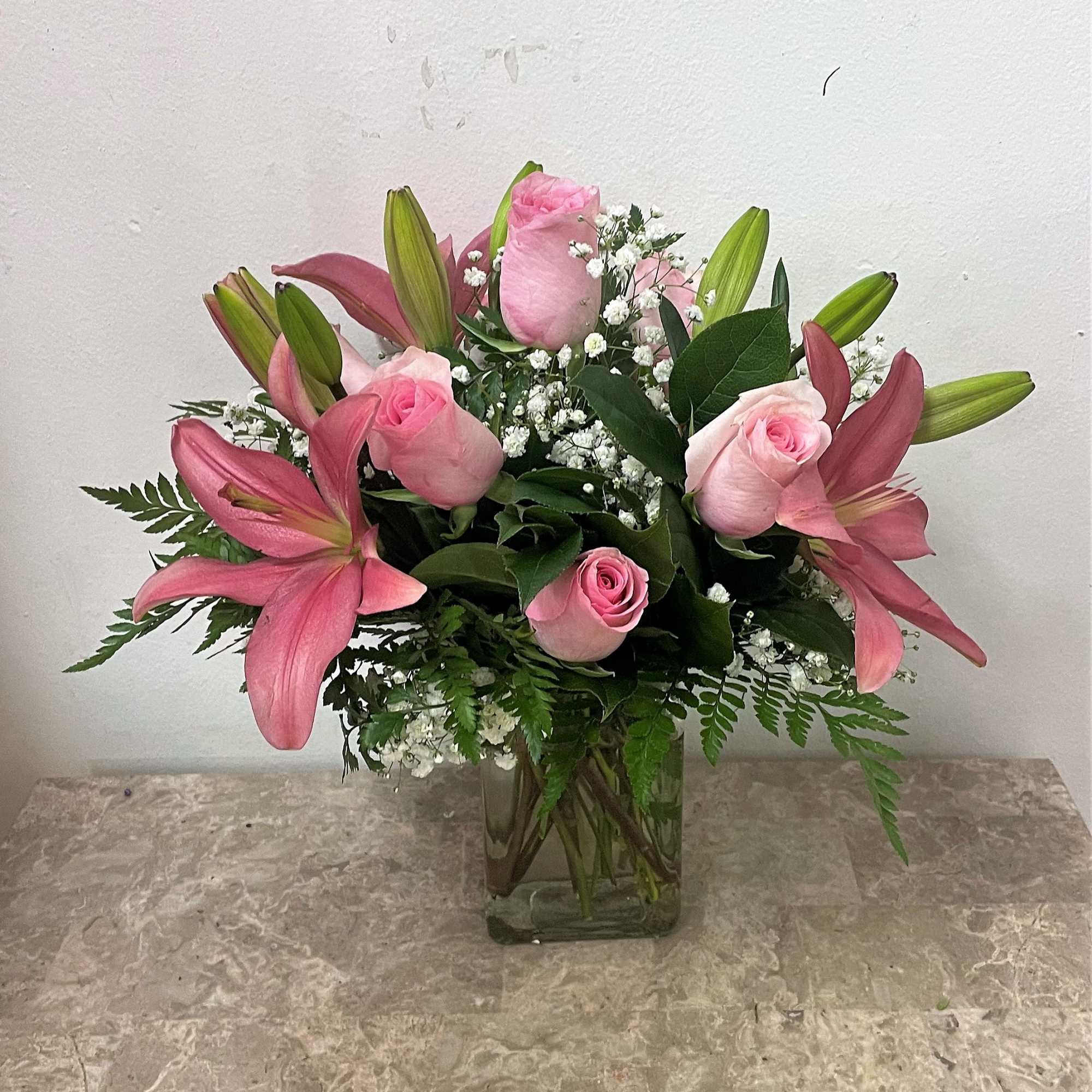 Pink roses and lilies arranged in a clear glass vase