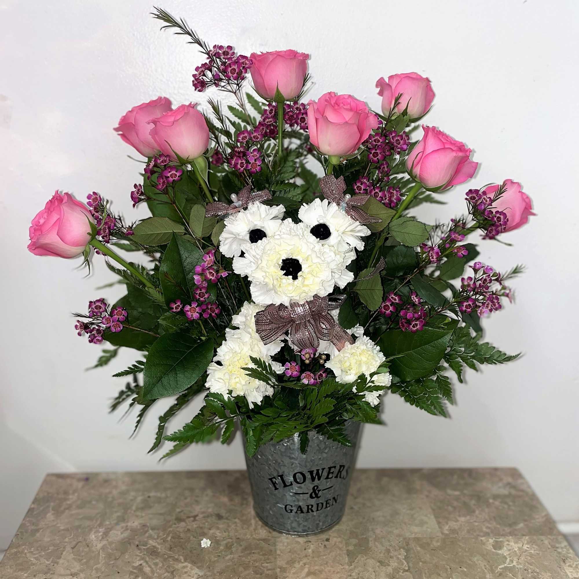 Pink roses and white carnations arranged in a metal bucket