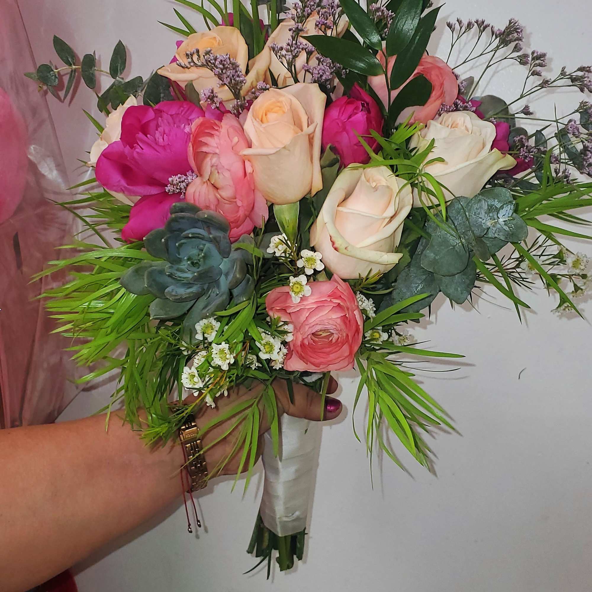 Hand-tied bouquet of pink and cream roses with mixed greenery