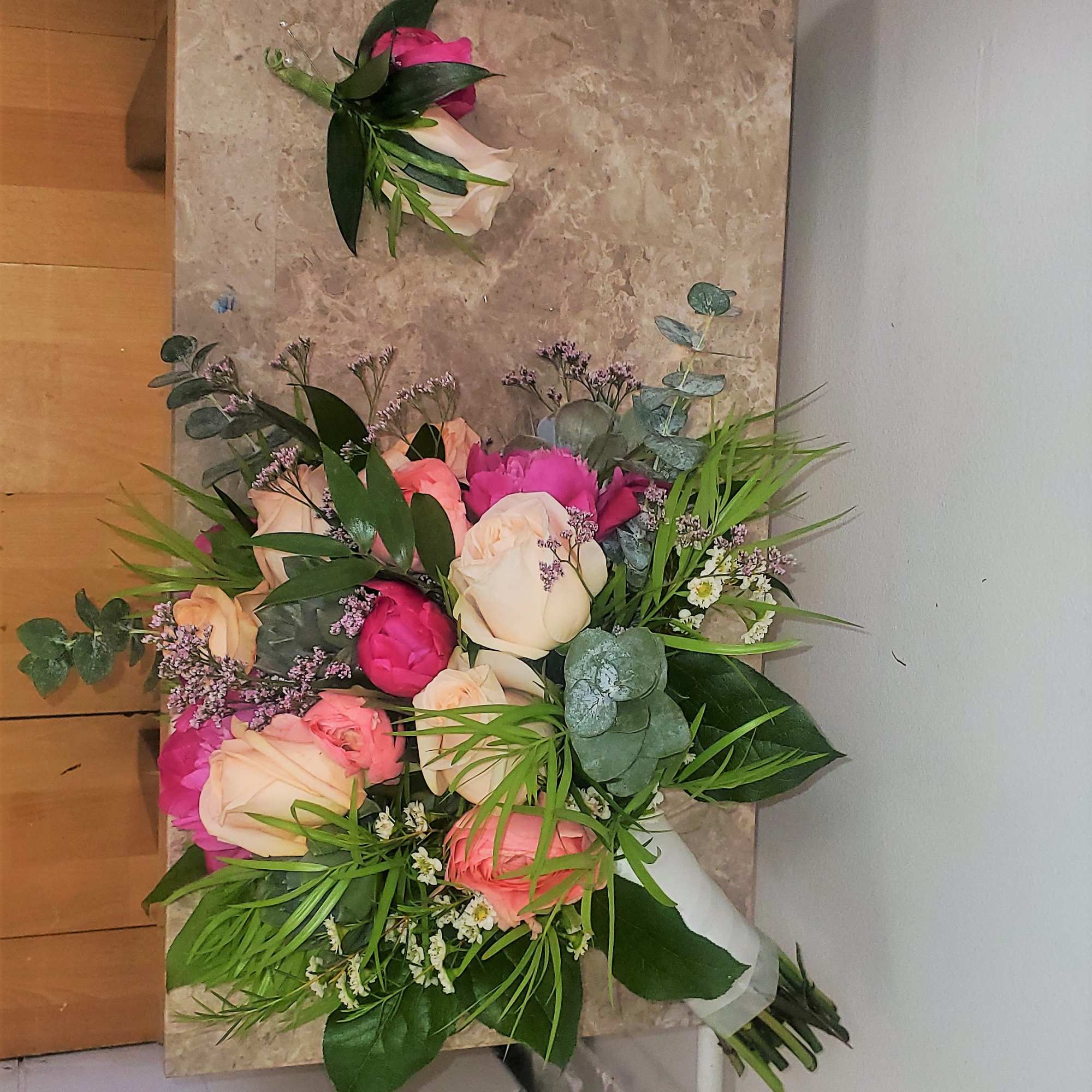 Bouquet of pink and cream roses with greenery and a matching boutonniere