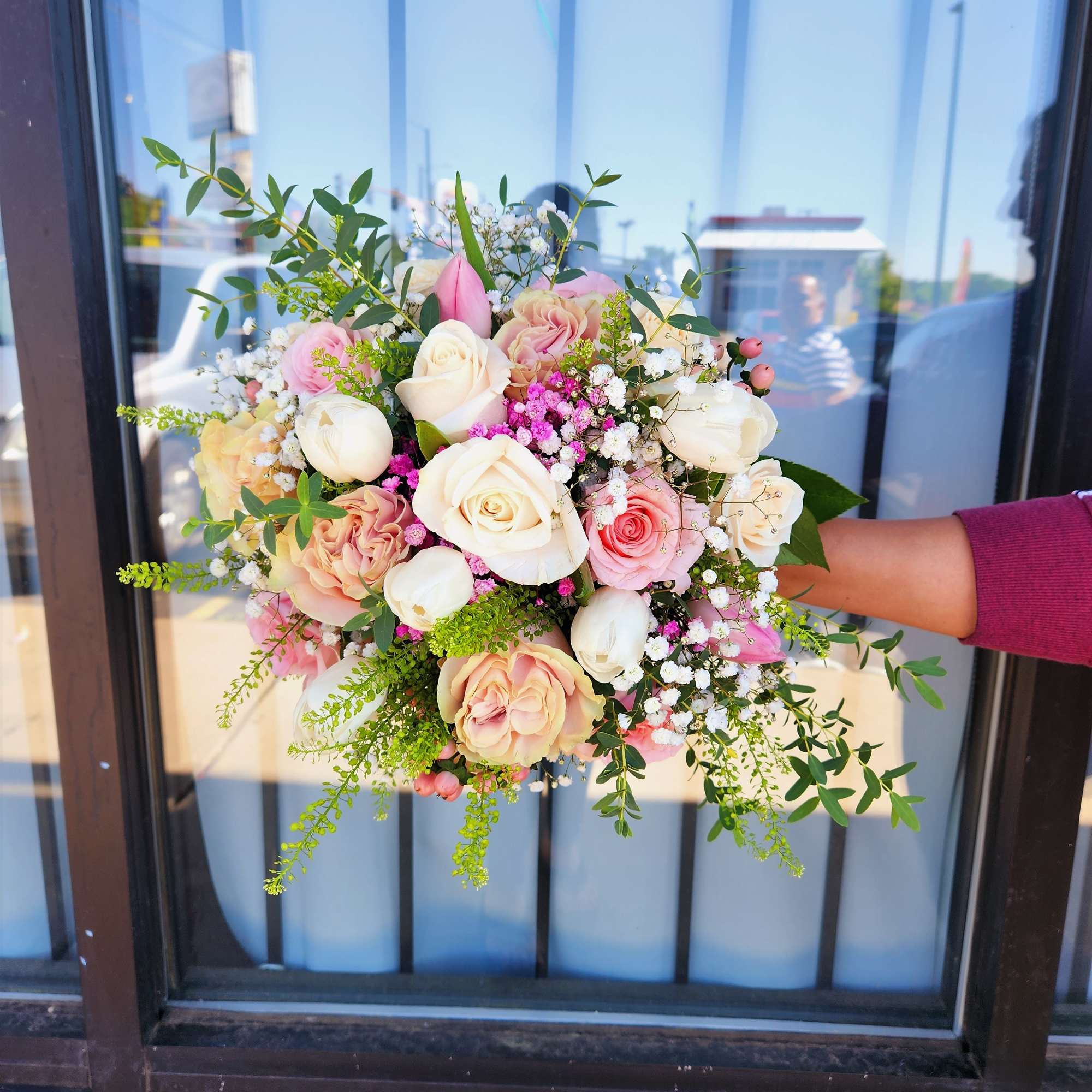 Handheld bouquet of pink and white roses with baby's breath