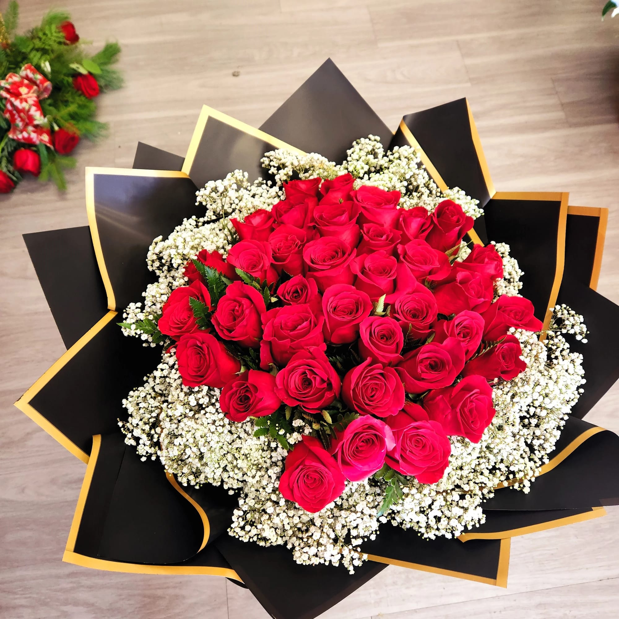 Large bouquet of red roses with white baby's breath in black and gold wrap