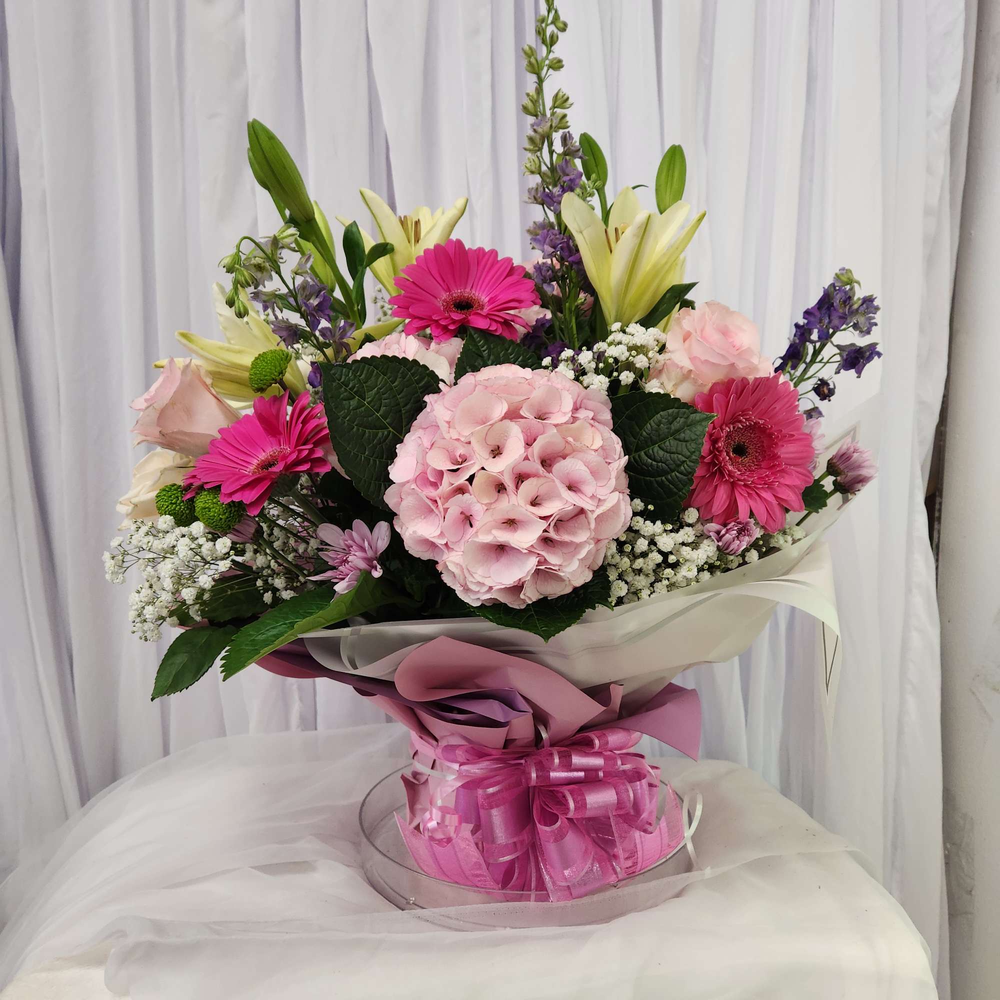 Pink and white bouquet with lilies, gerbera daisies, and hydrangea in wrap