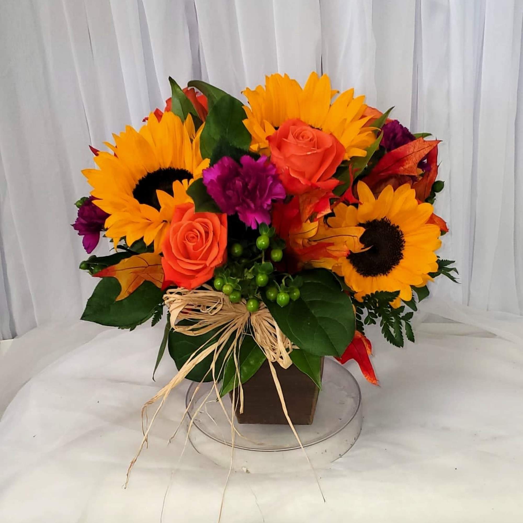 Bouquet of sunflowers and orange roses in a square vase