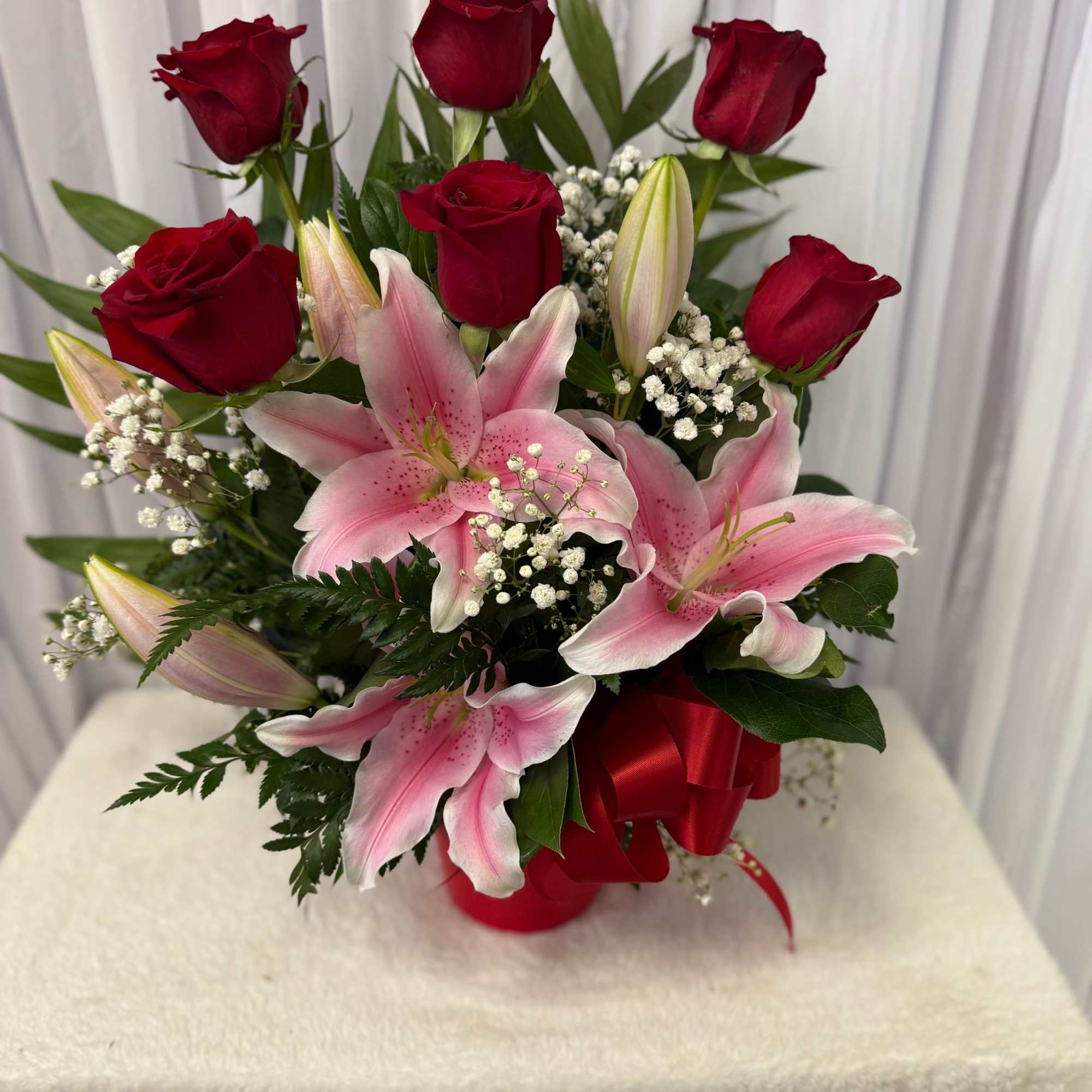 Bouquet of red roses and pink lilies with baby's breath in a red ribbon wrap