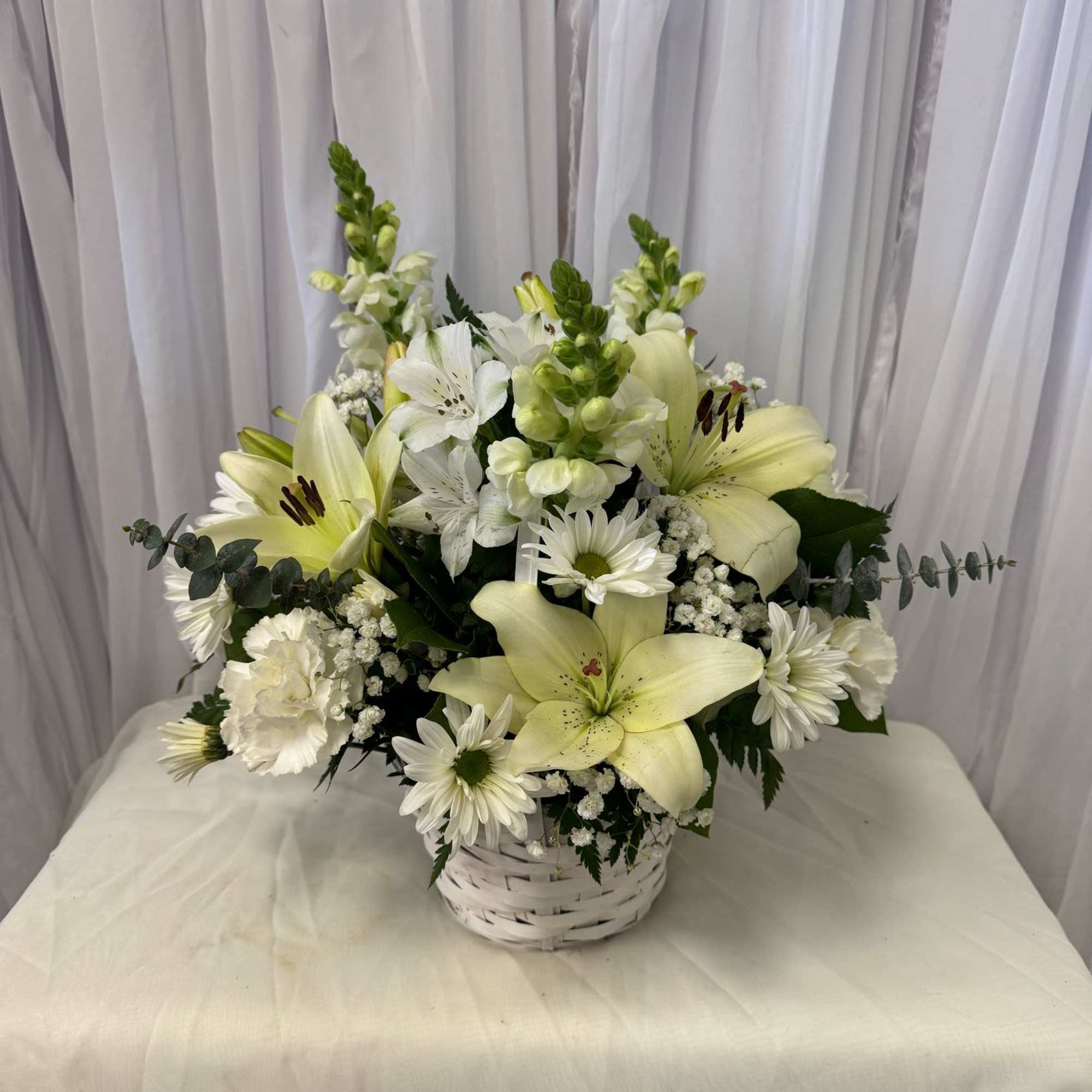 White lilies and daisies arranged in a white basket