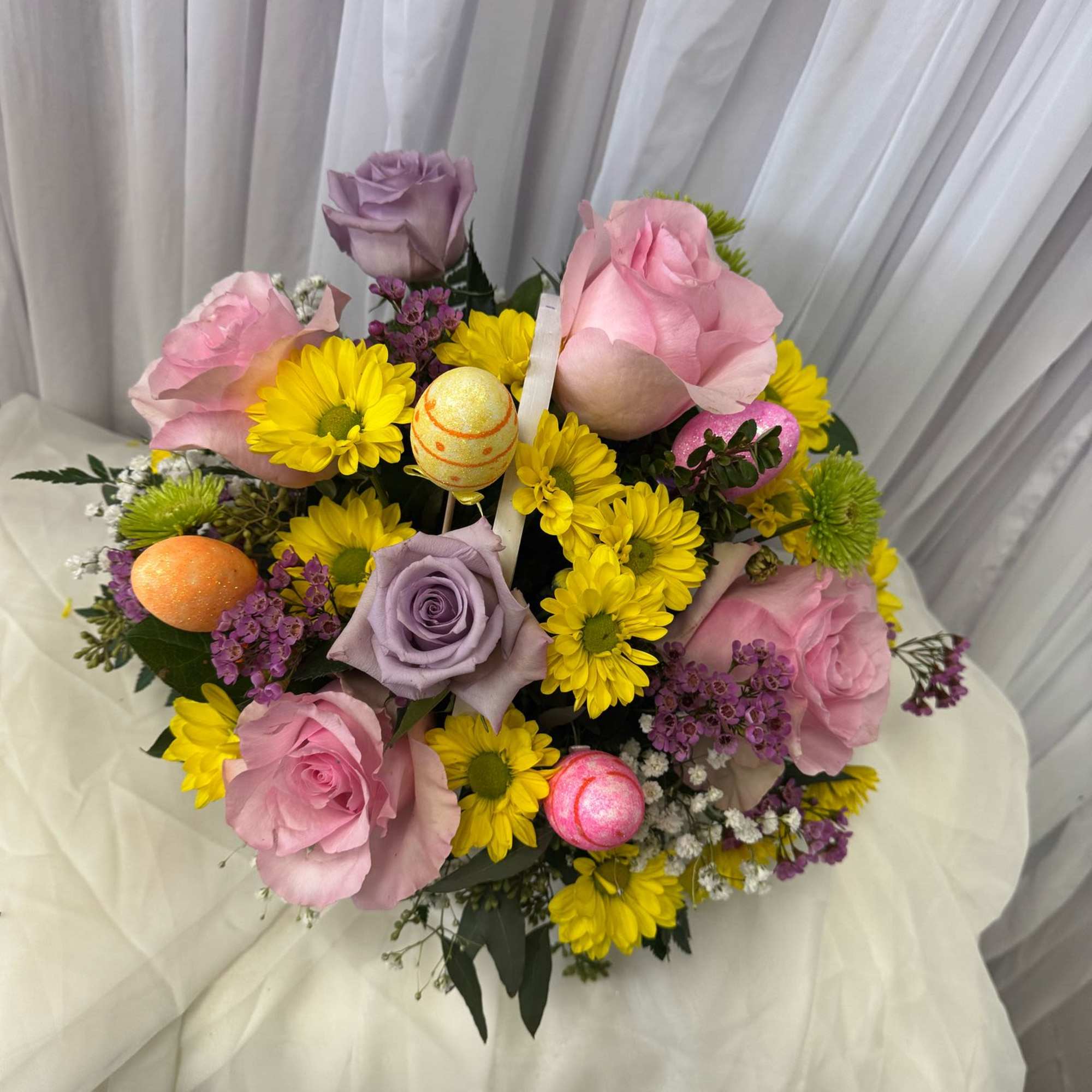 Bouquet of pink and lavender roses with yellow daisies and decorative eggs