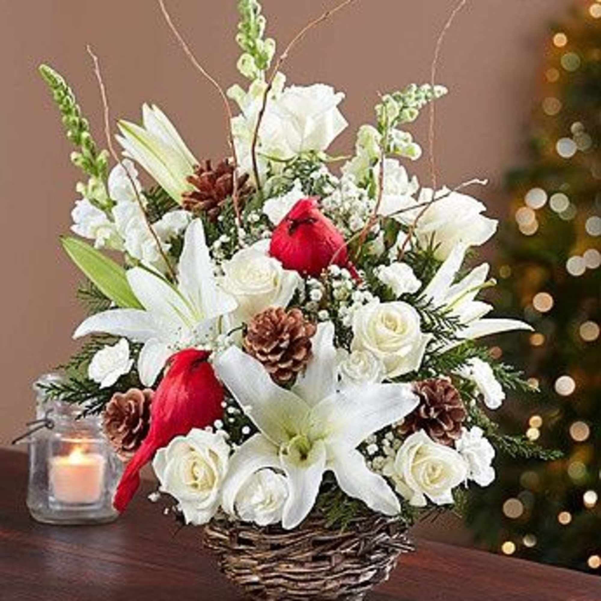 White lilies and roses in a wicker basket with red accents and pinecones