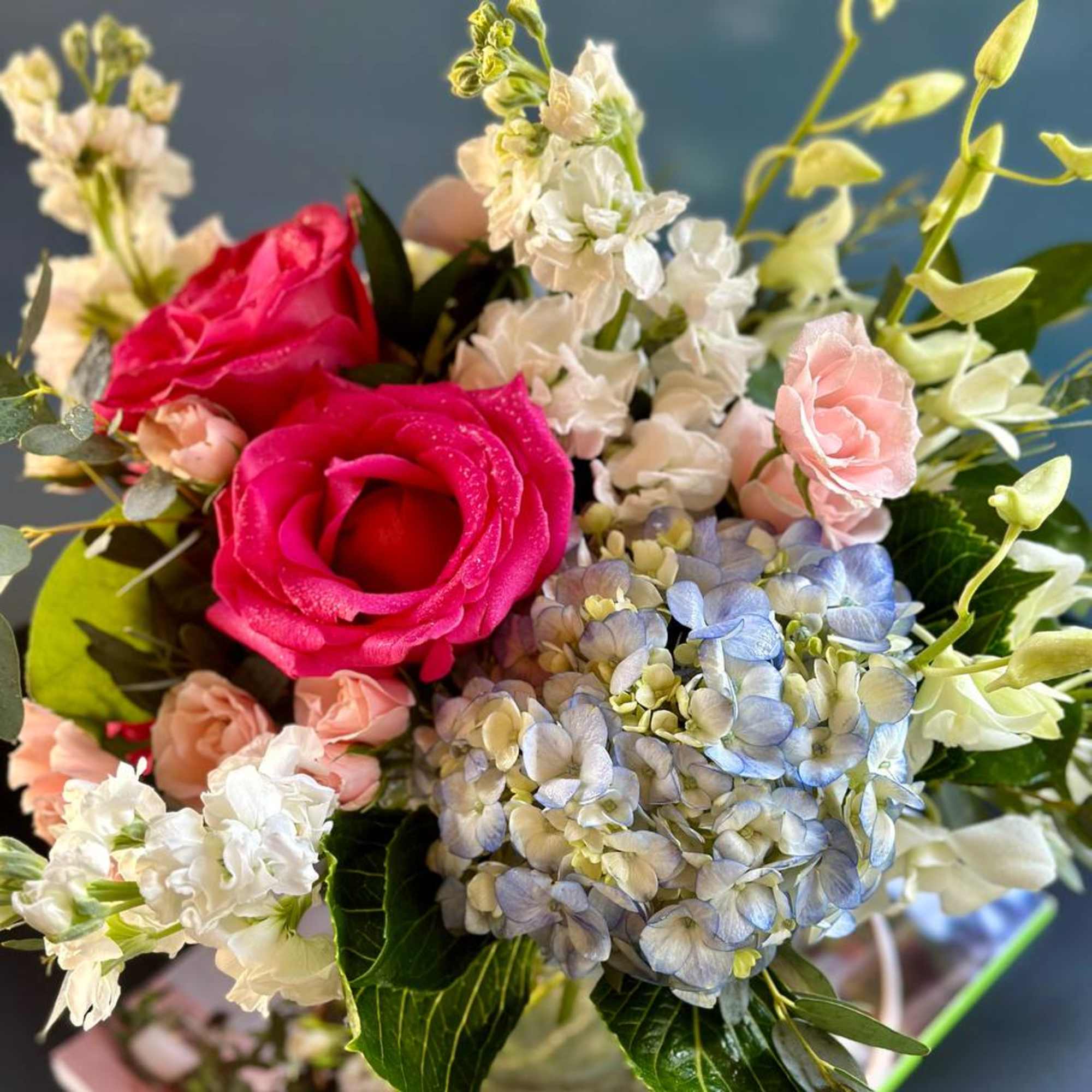 Bouquet of hot pink roses, pale hydrangea, and white blossoms