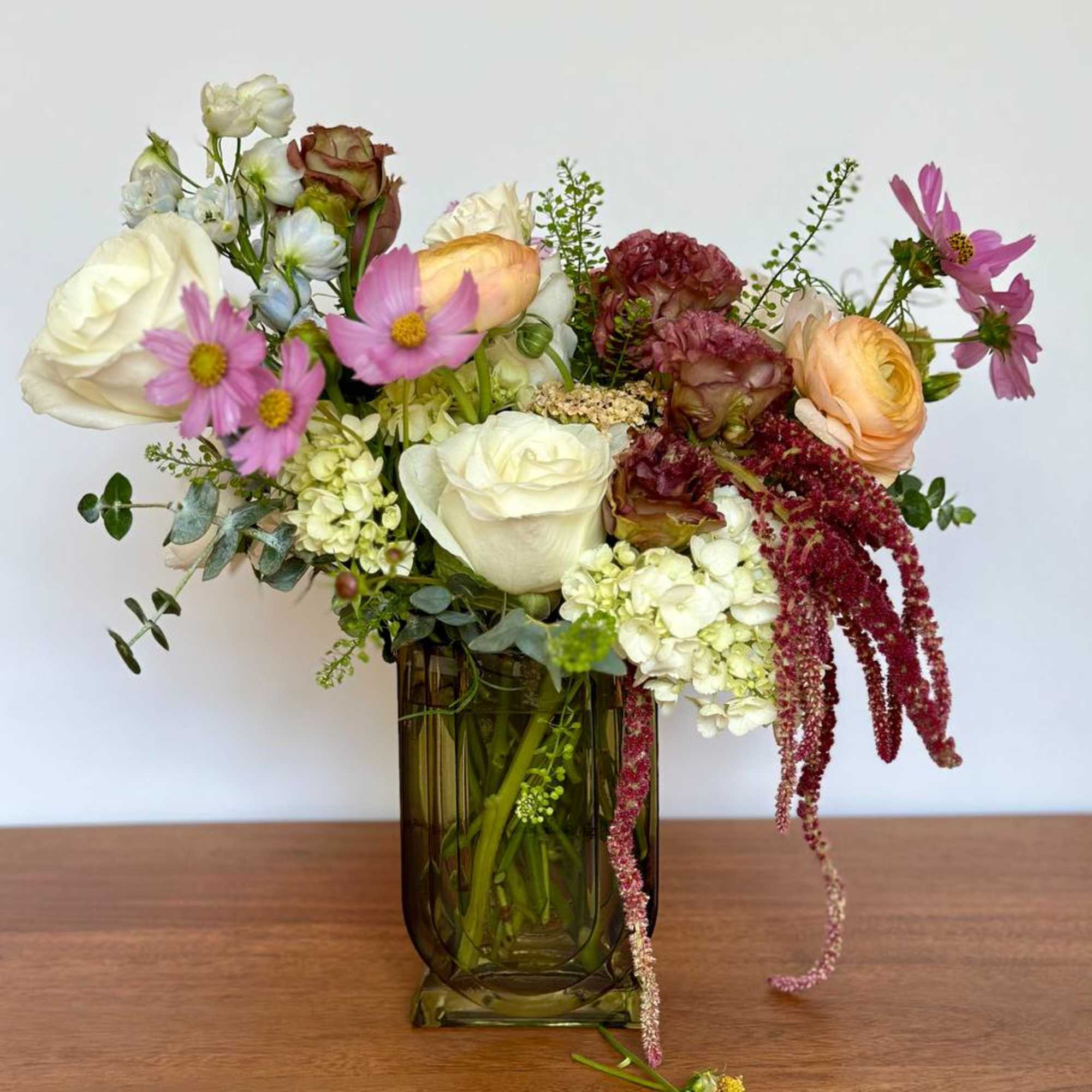 Mixed bouquet of roses, cosmos, and hydrangeas in a glass vase