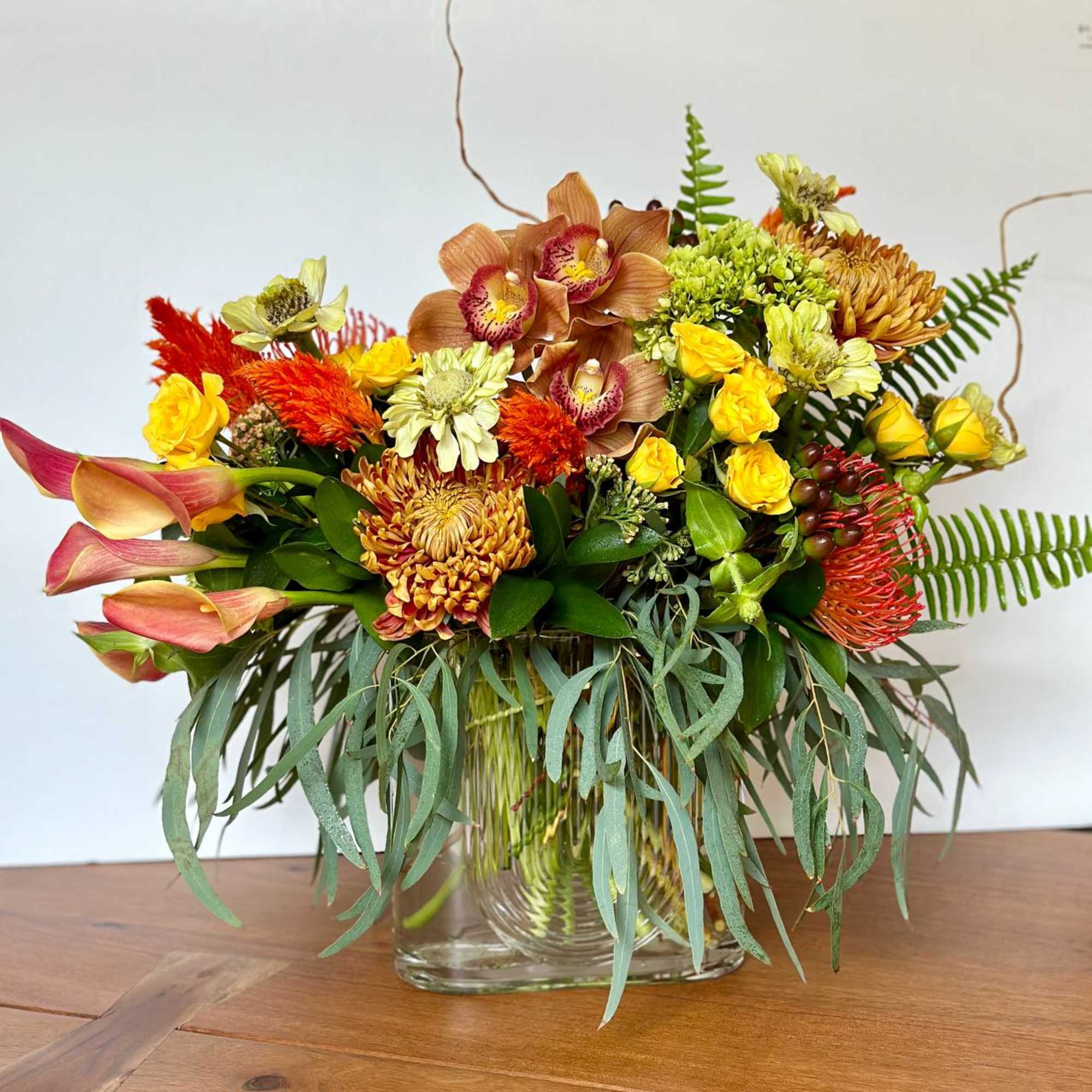 Mixed bouquet in a clear glass vase with yellow, orange, and pink flowers