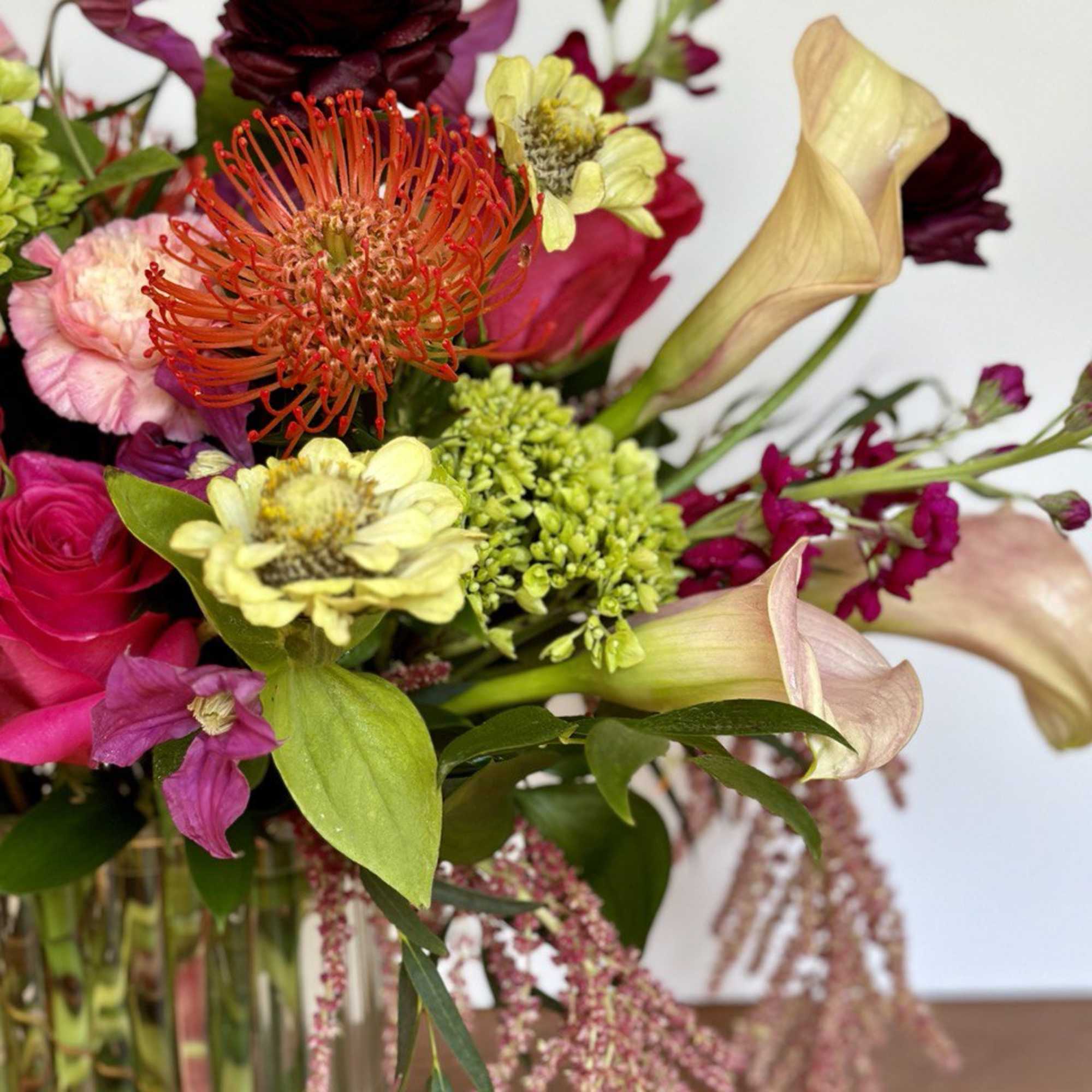 Colorful mixed bouquet in a glass vase with calla lilies and bright blooms