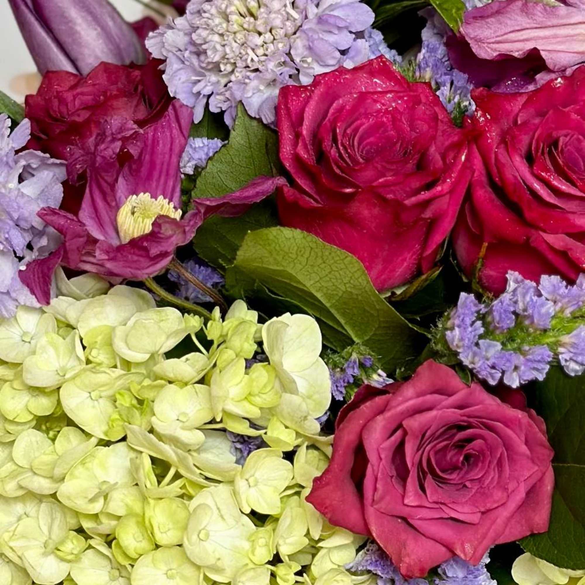 Close-up bouquet of pink roses, hydrangeas, and lavender flowers