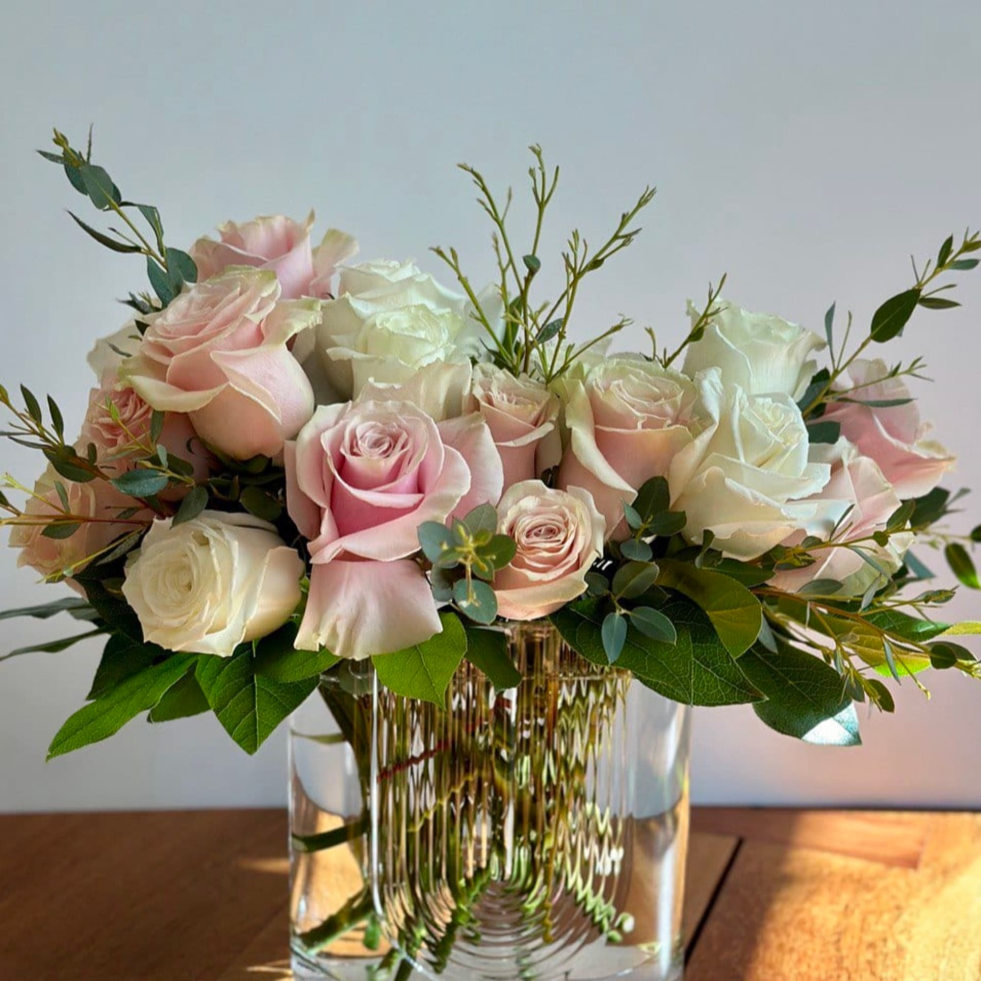Pink and white roses arranged in a clear glass vase