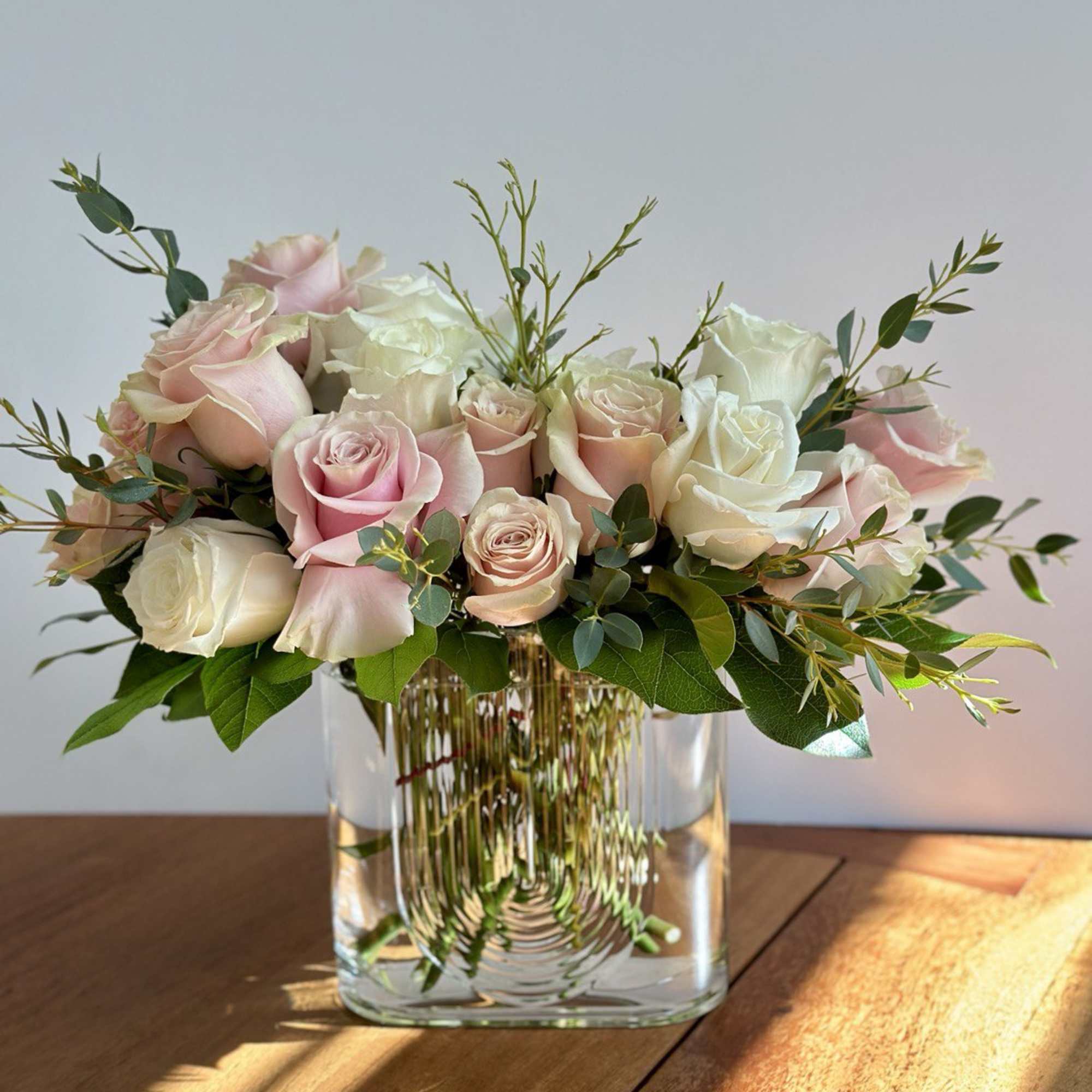 Pink and white roses arranged in a clear glass vase, photo 2 of 3