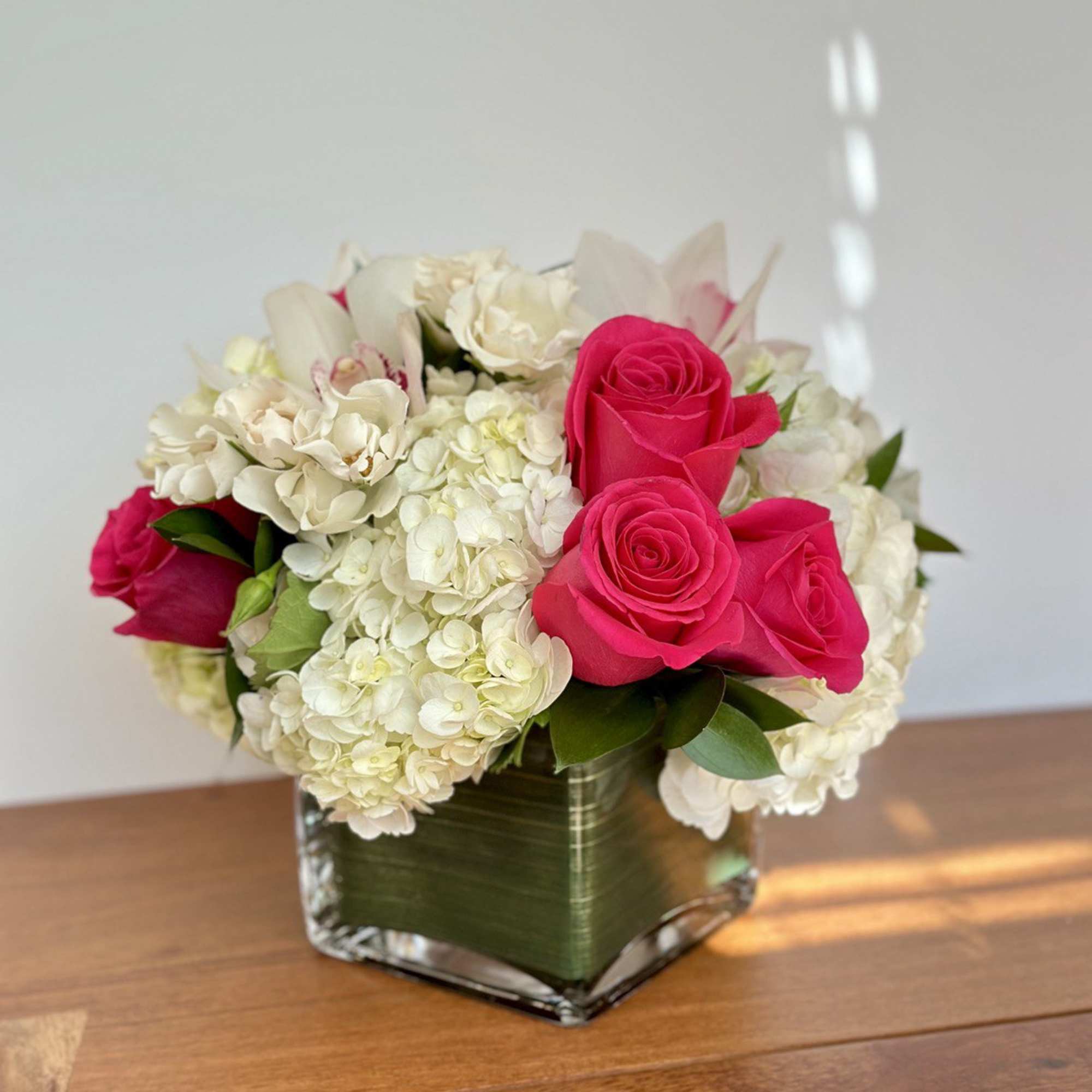 Pink roses and white hydrangeas in a square glass vase