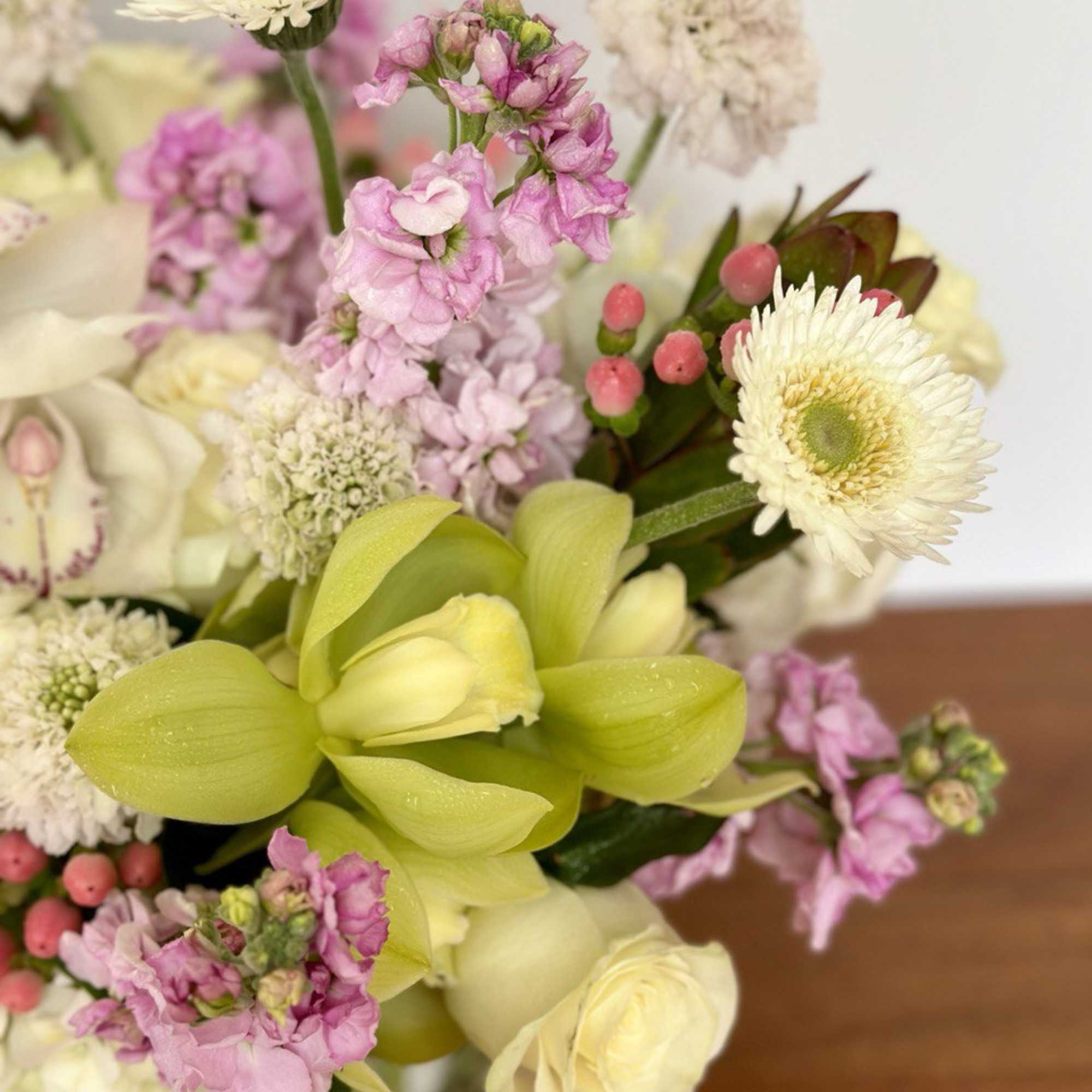 Bouquet of pale pink and white flowers with green orchid blooms