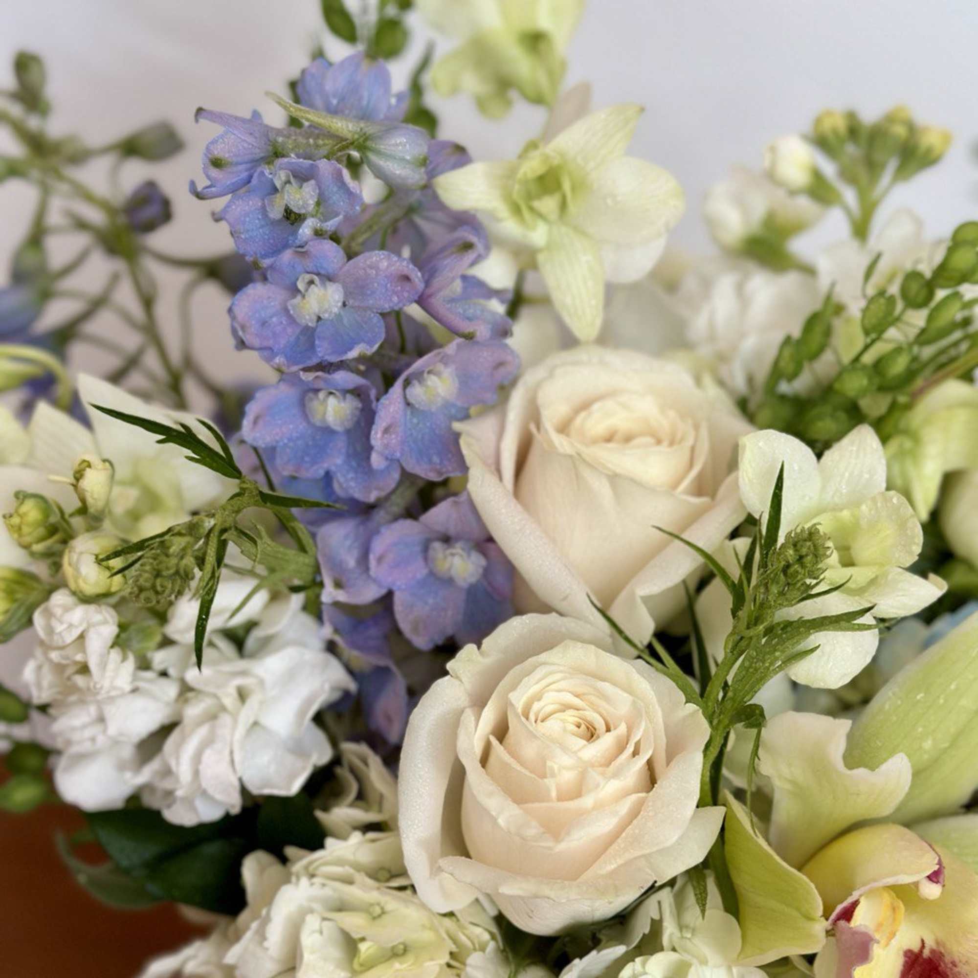 Bouquet of cream roses, blue delphinium, and white orchids