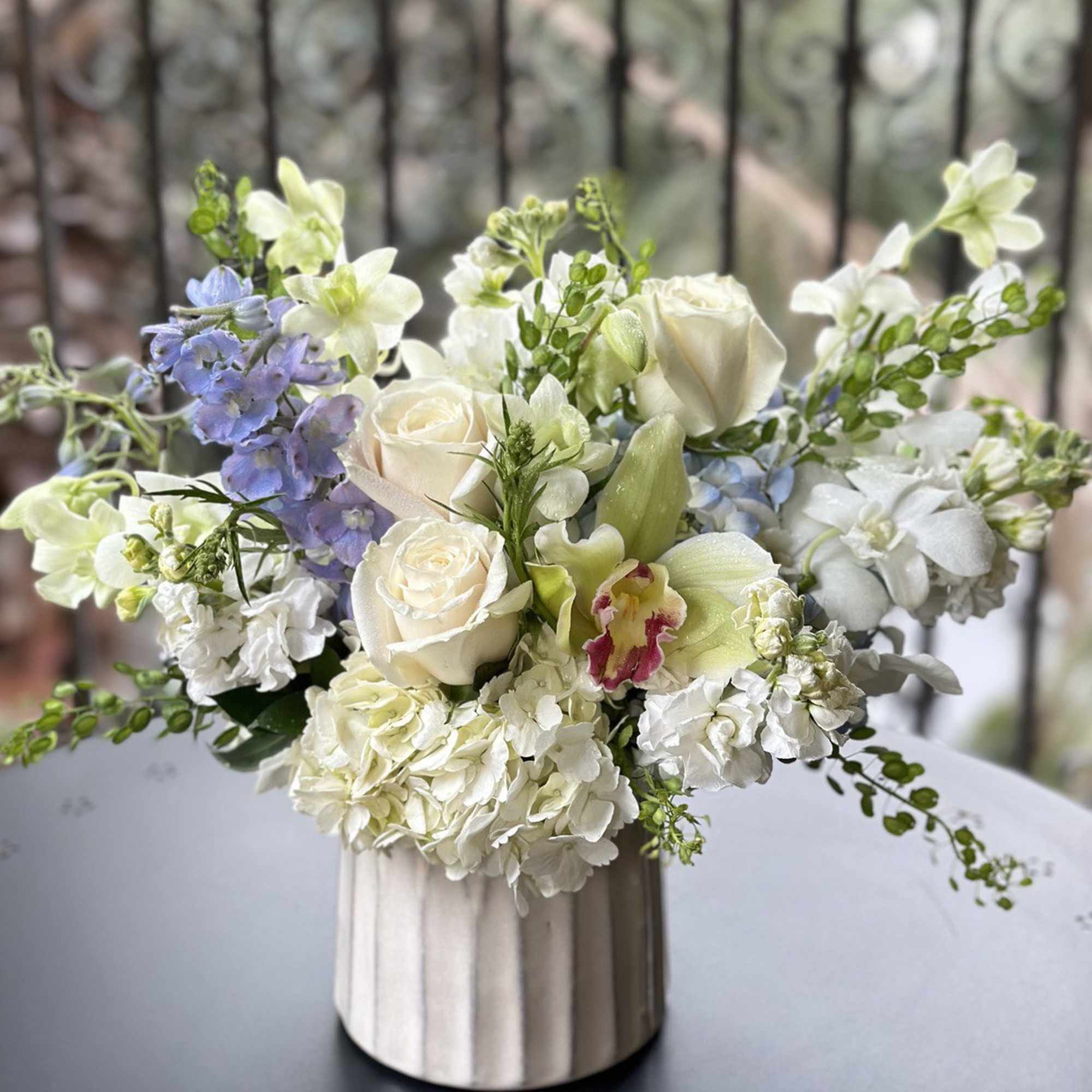 White and pale blue floral arrangement in a ribbed vase