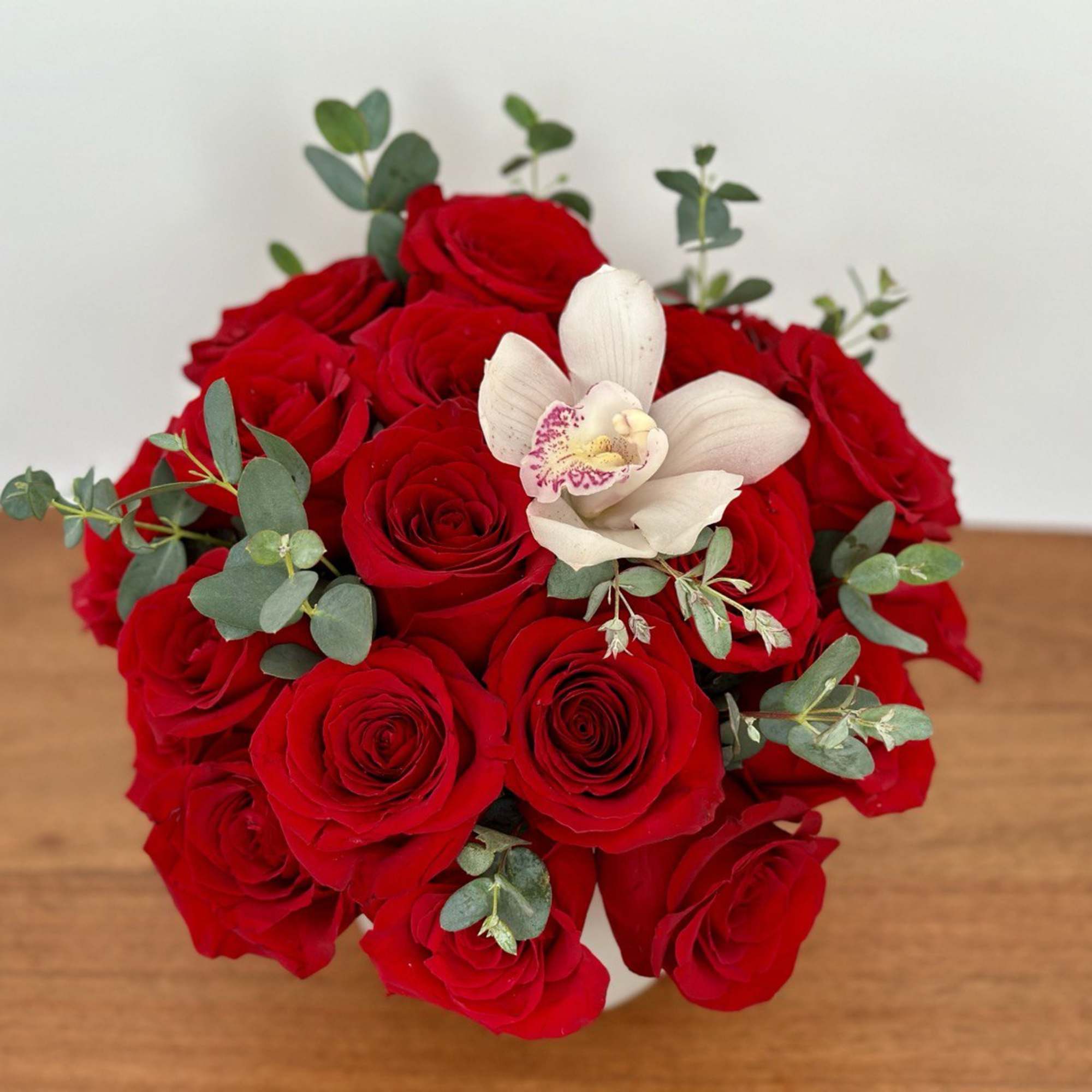 Bouquet of red roses with a white orchid accent
