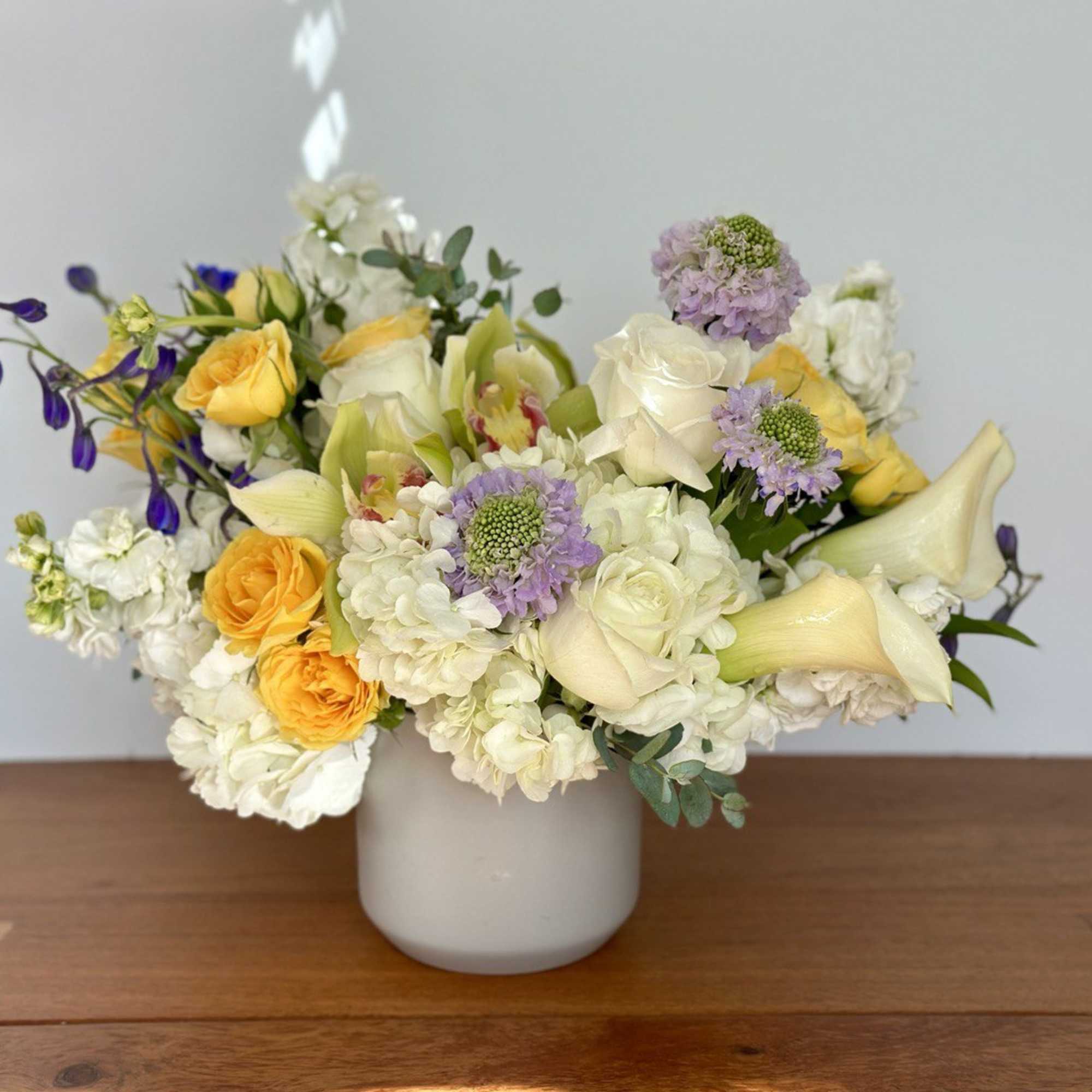 Mixed bouquet of white, yellow, and lavender flowers in a white vase
