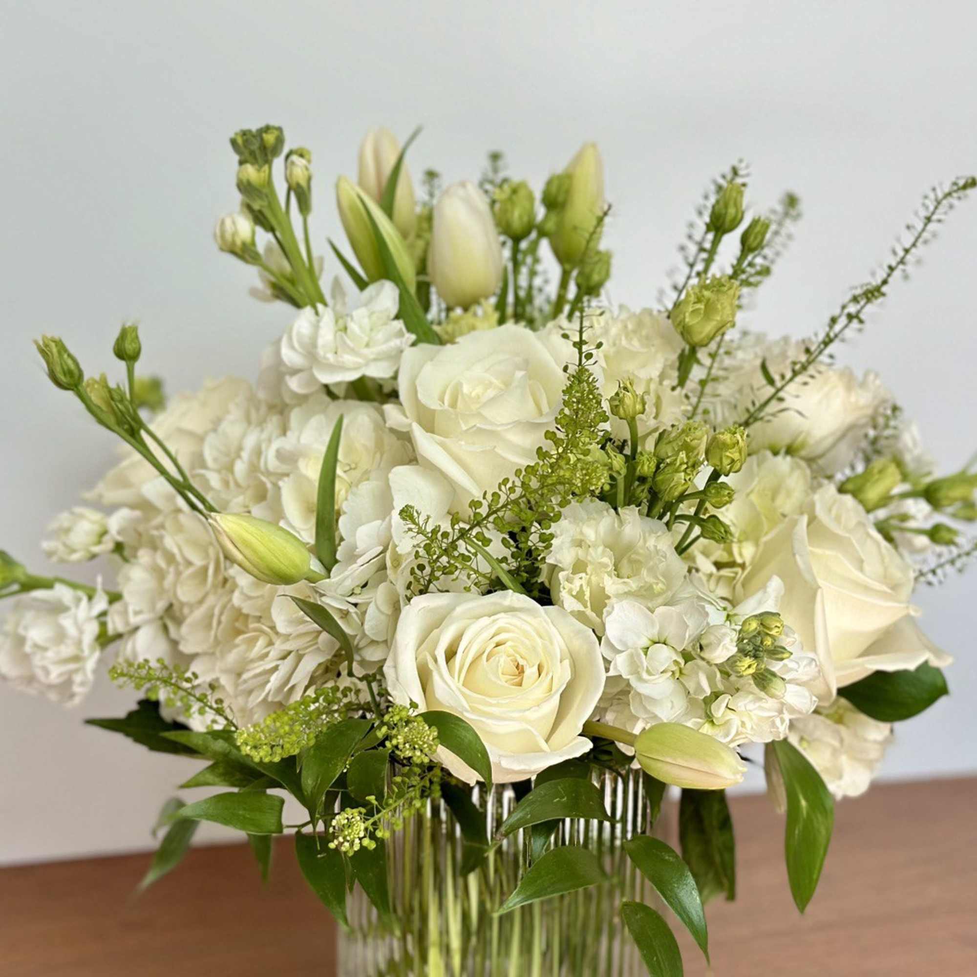 White roses and hydrangeas arranged in a clear glass vase