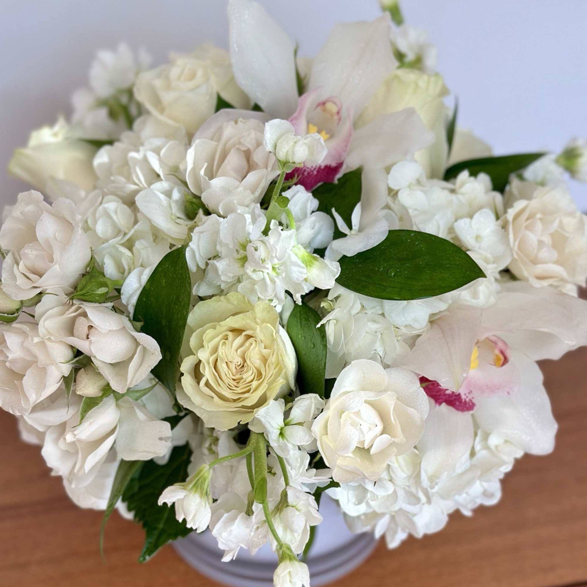 White floral bouquet with roses and orchids in a vase
