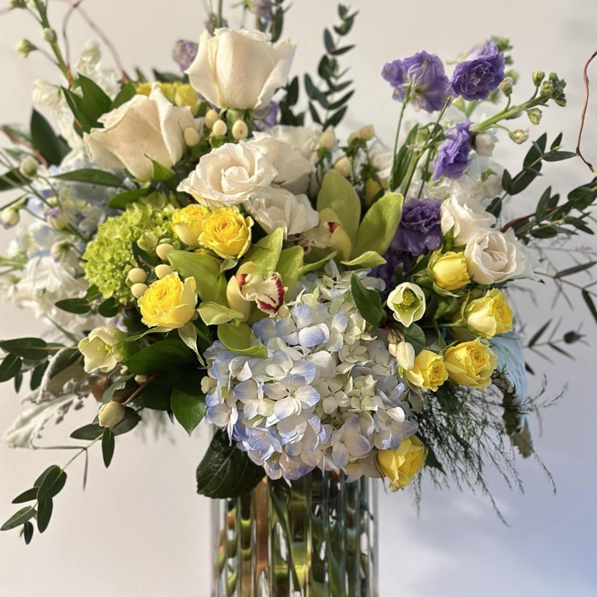 Mixed bouquet of white, yellow, and purple flowers in a glass vase