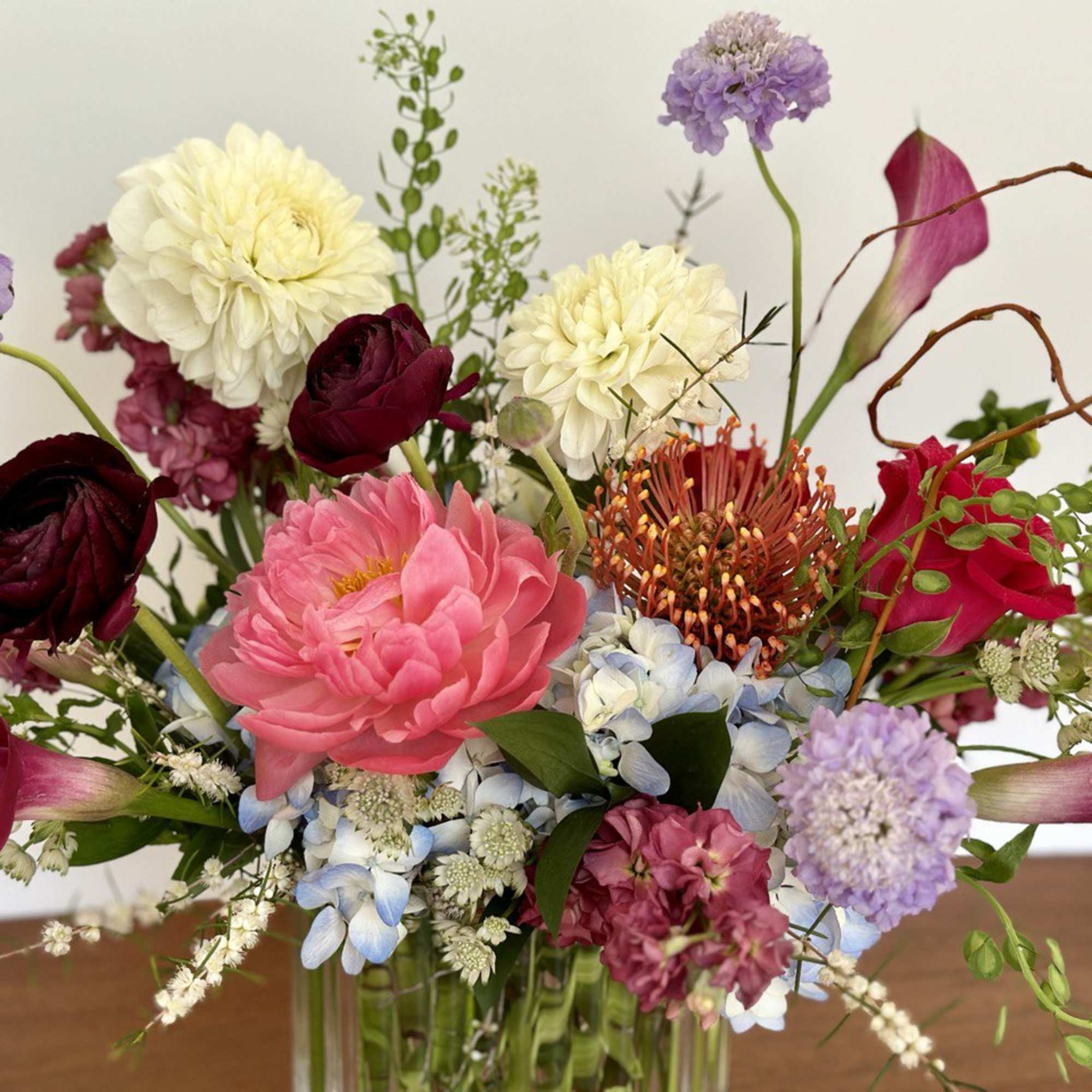 Mixed bouquet with pink, purple, white, and orange flowers in a glass vase