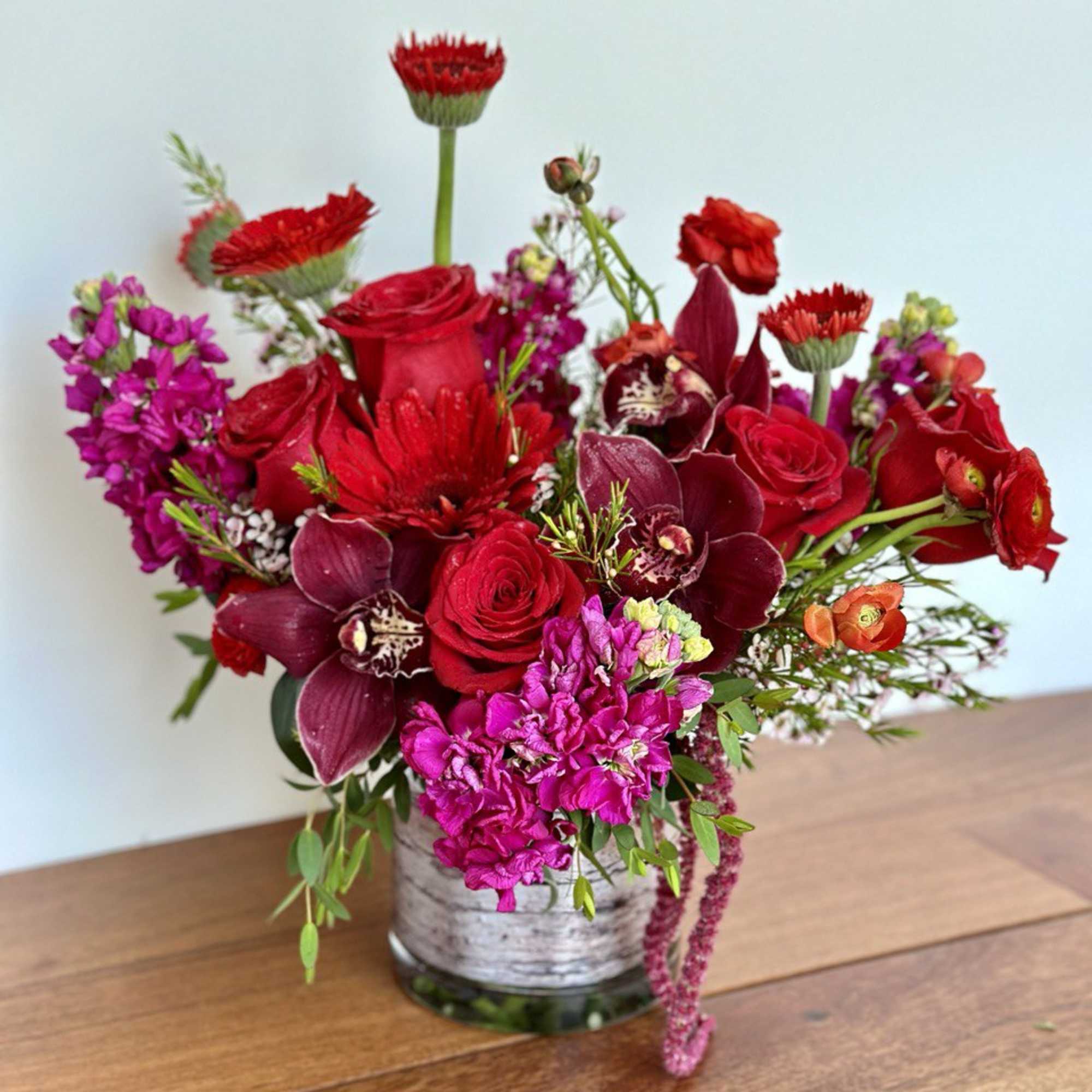 Red and magenta floral arrangement in a glass vase