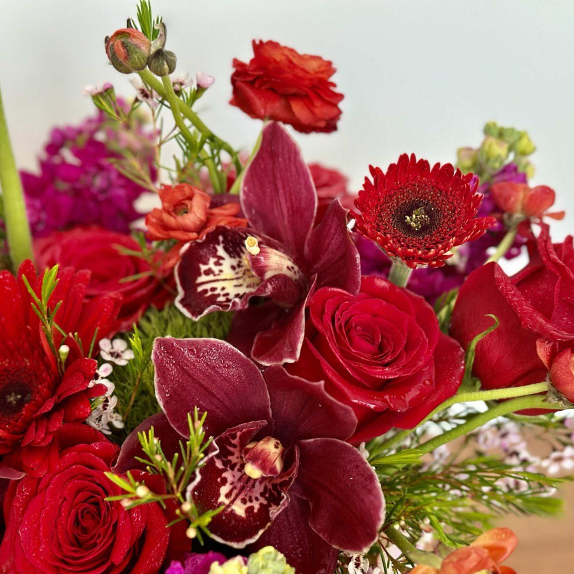 Red roses and burgundy orchids in a mixed bouquet