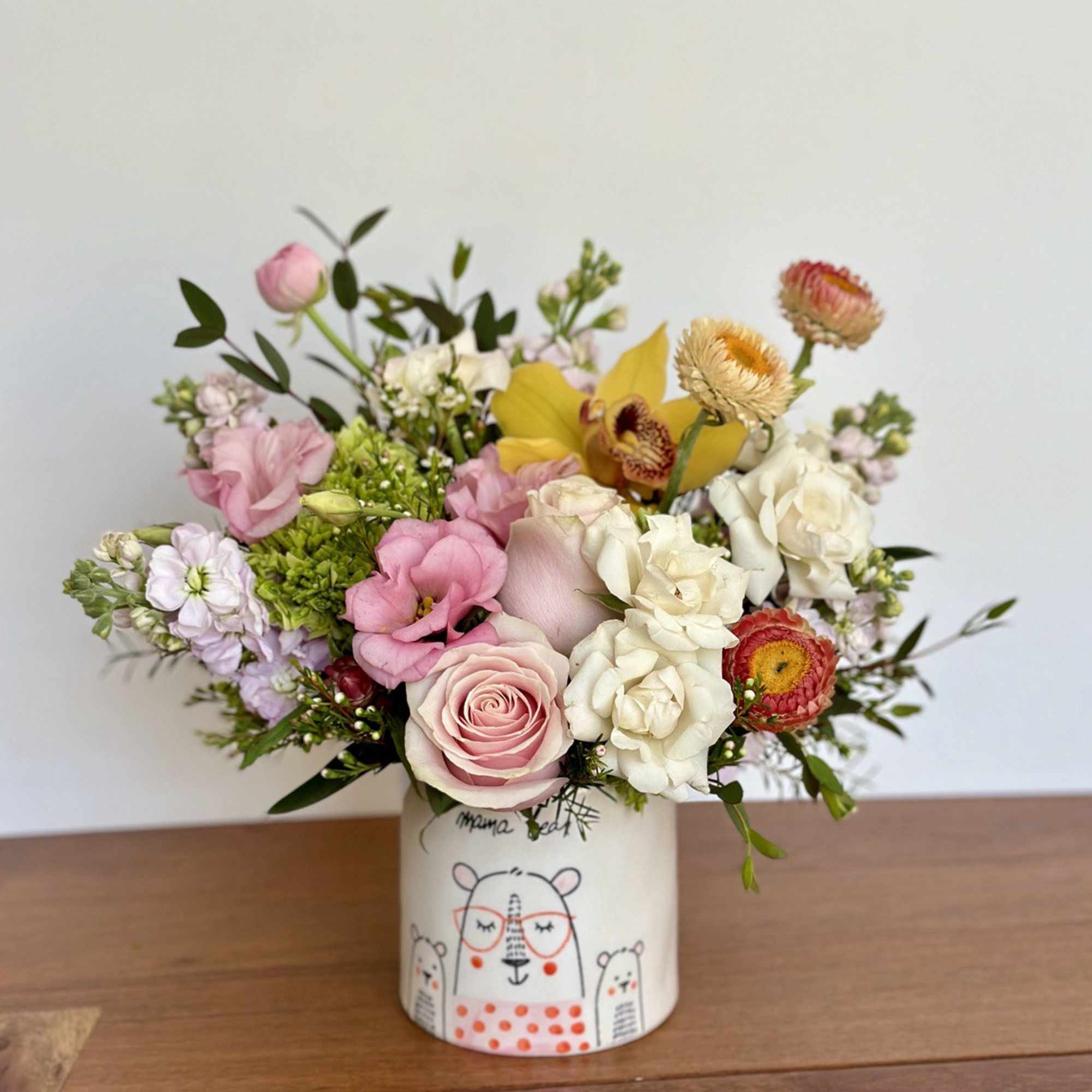 Mixed bouquet of pink, white, and yellow flowers in a decorated ceramic vase